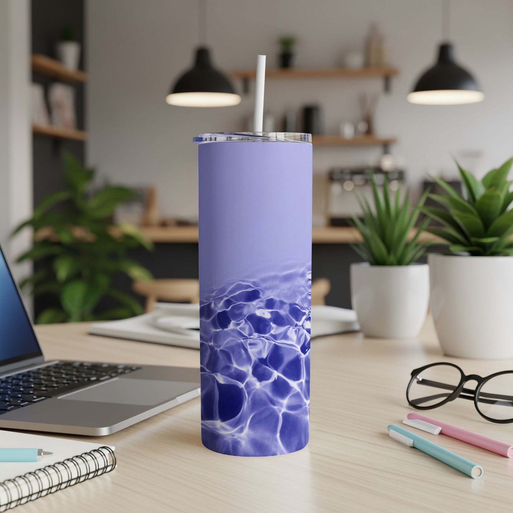 Purple tumbler with water ripple design on desk with laptop.