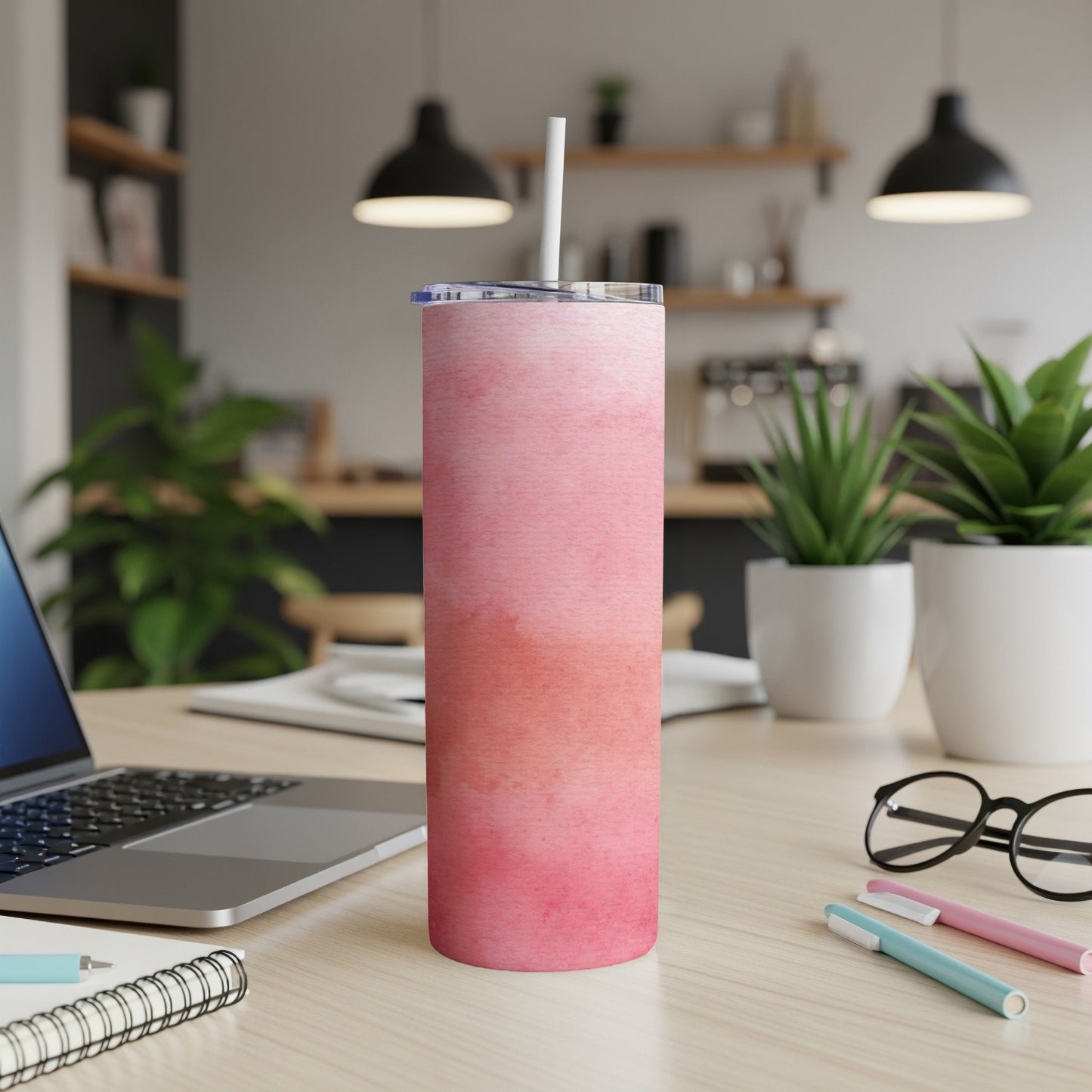 Pink watercolor gradient insulated tumbler with straw on a desk.
