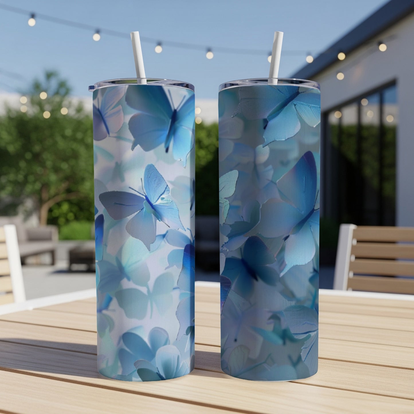 Two blue butterfly print tumblers with straws on a table.