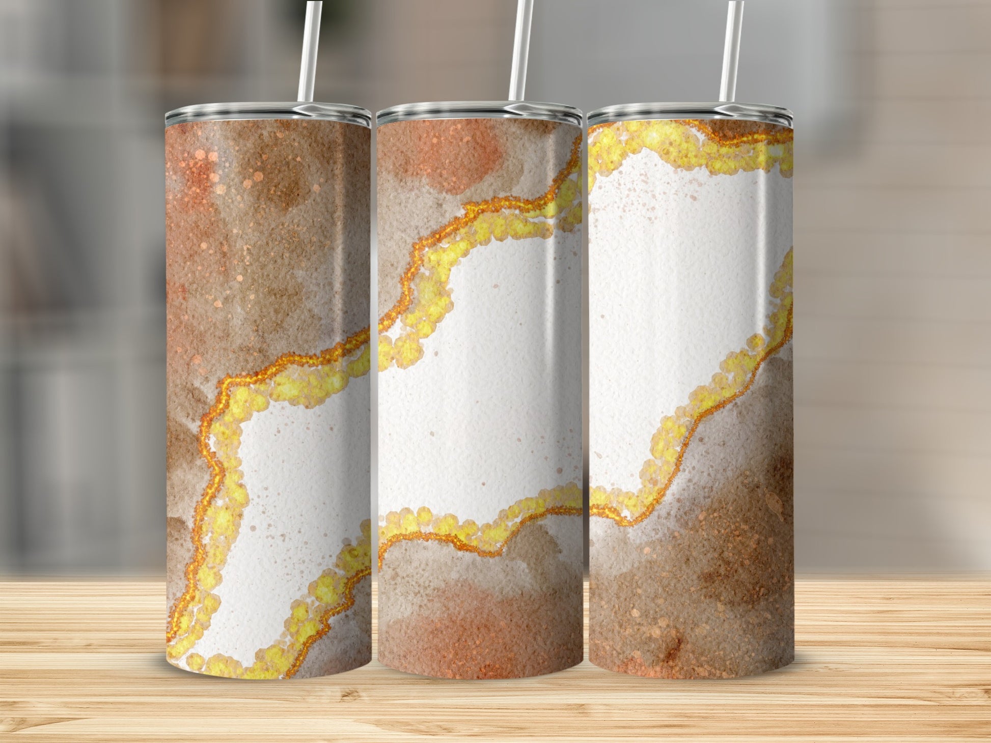 Three tumblers with marbled brown and gold glitter design on a wooden surface.