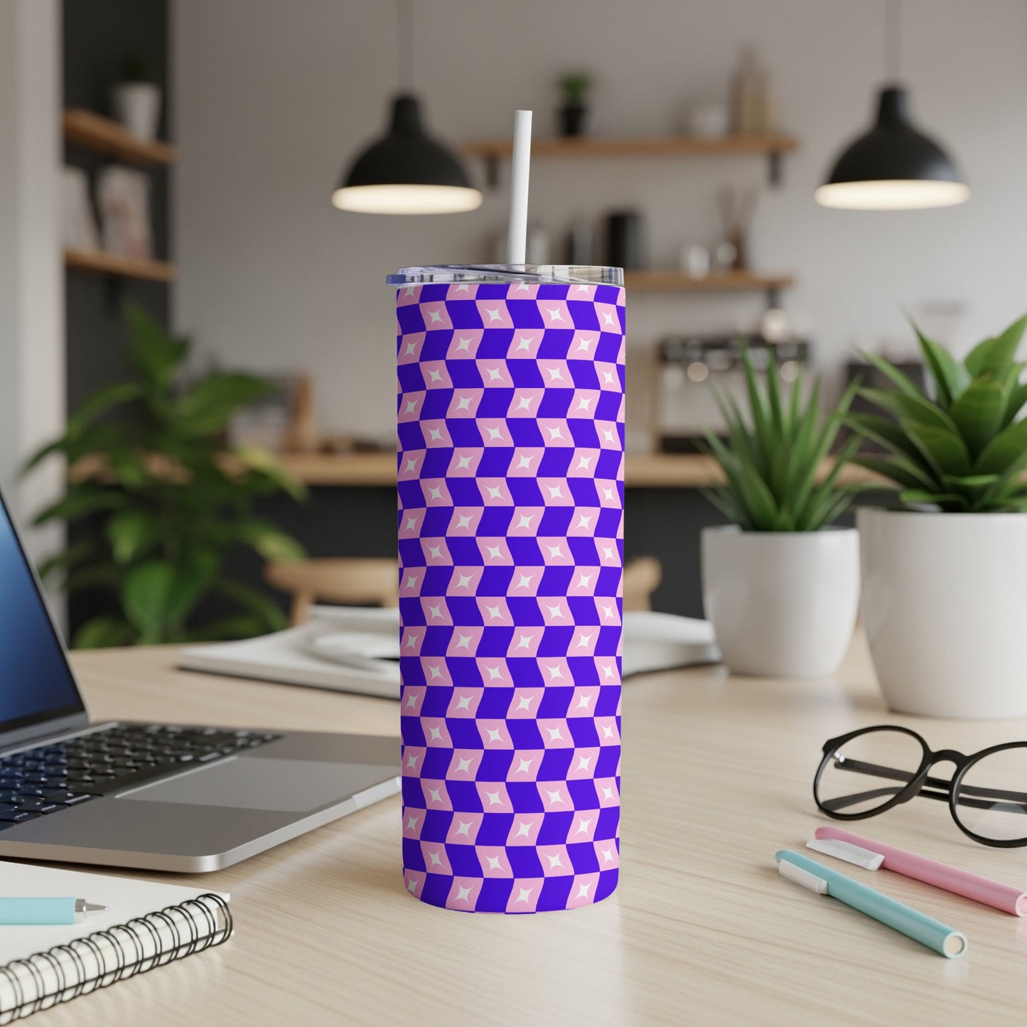 Blue and pink geometric pattern tumbler with straw on a desk.