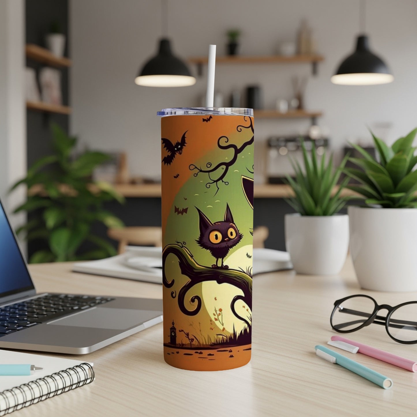 Orange tumbler with cartoon black cat, bats, and spooky tree on a desk.