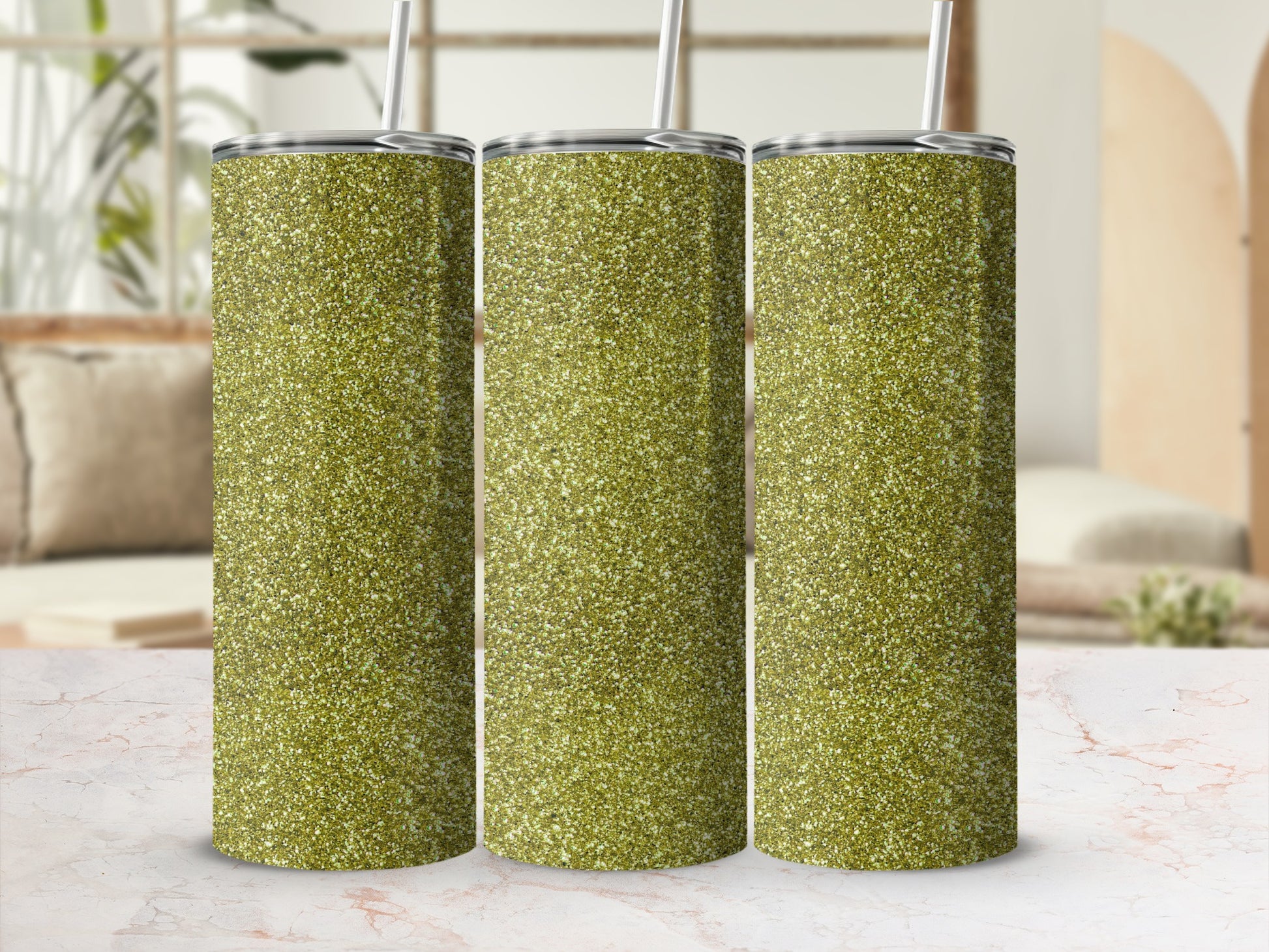 Three glittery green tumblers with straws stand on a marble surface.