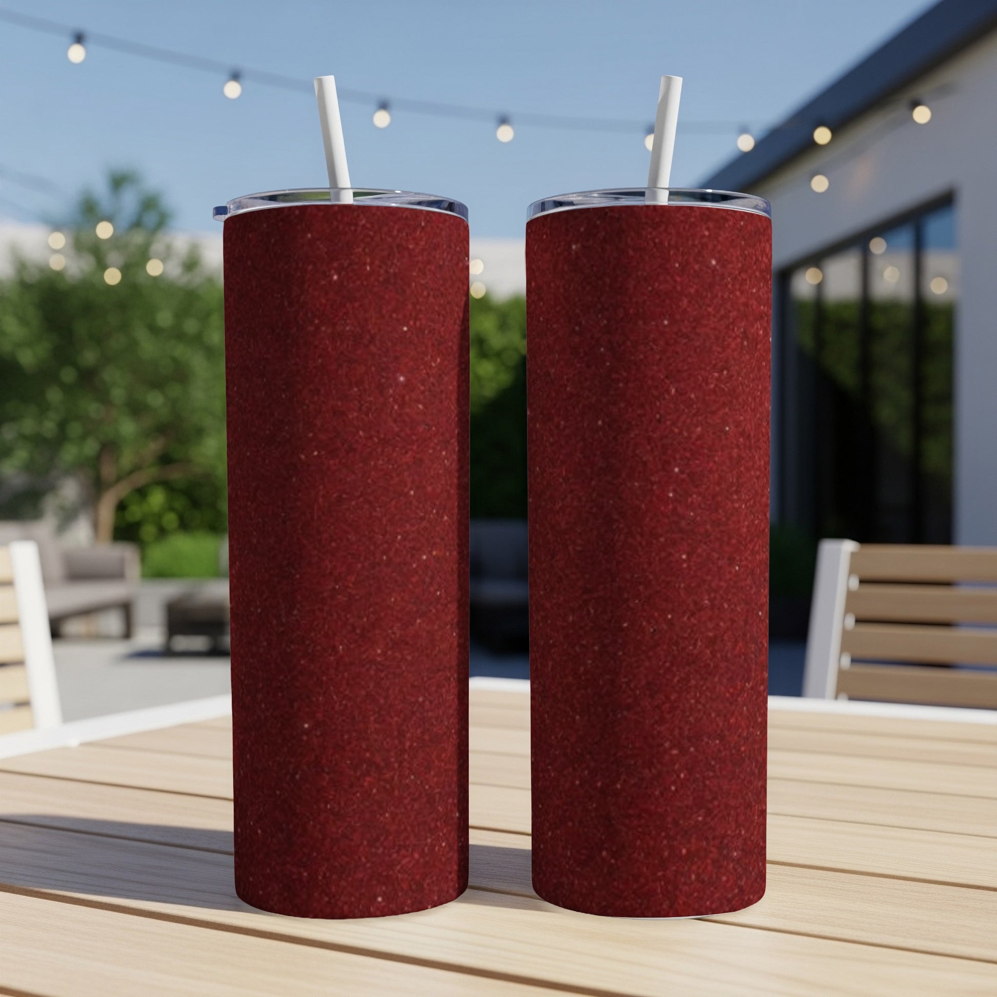 Two dark red glitter tumblers with white straws on a wooden table.