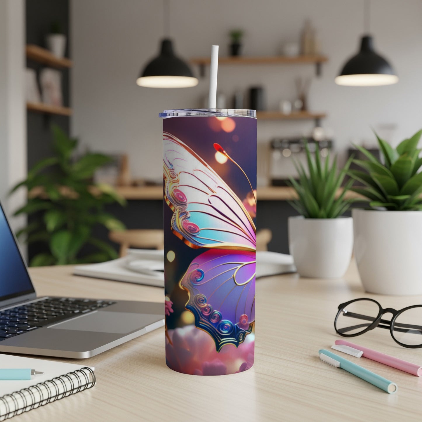 Tall tumbler with a colorful butterfly design and a straw, on a desk.