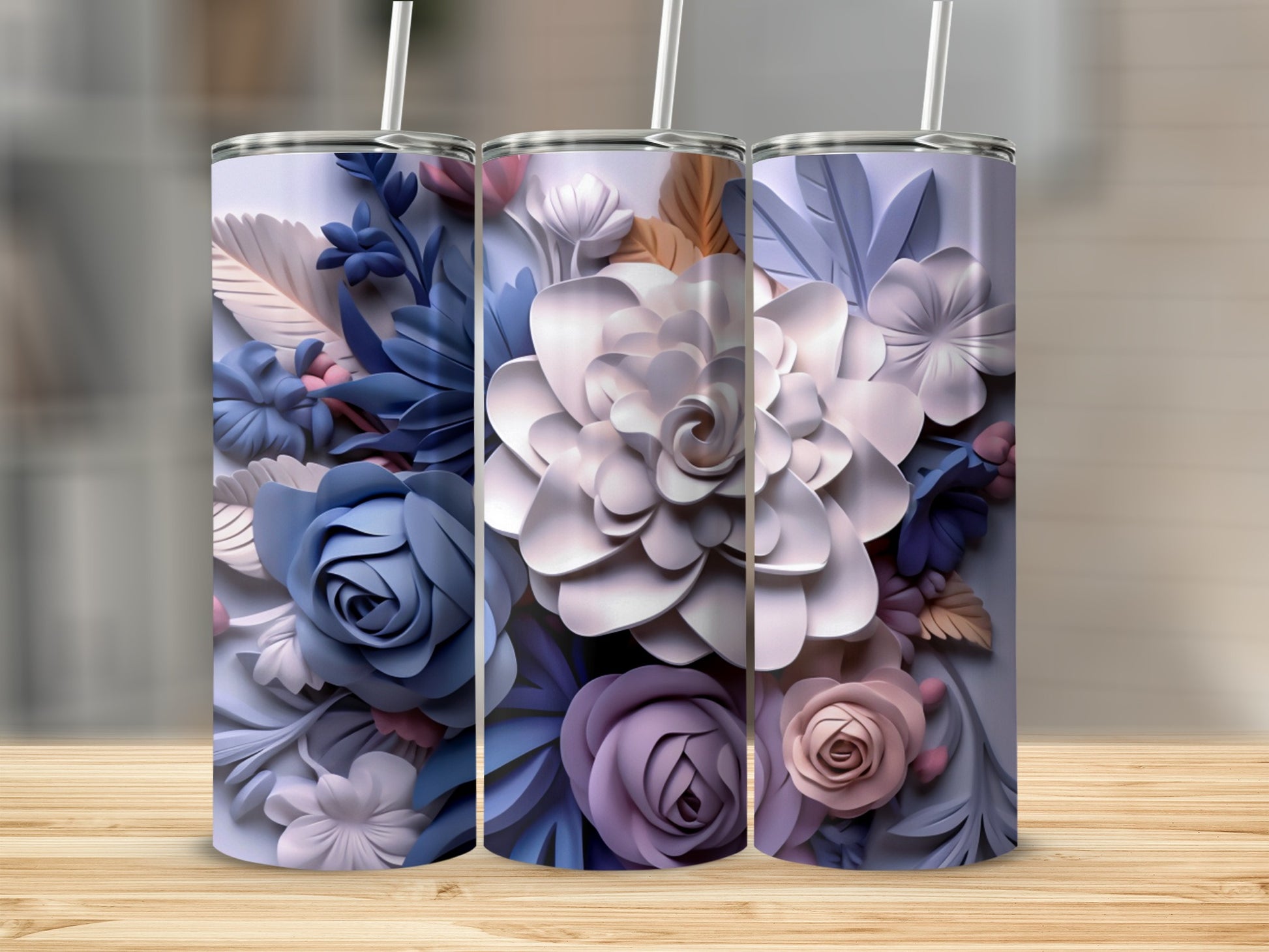 Three 3D floral pattern tumblers with straw on a wooden surface.