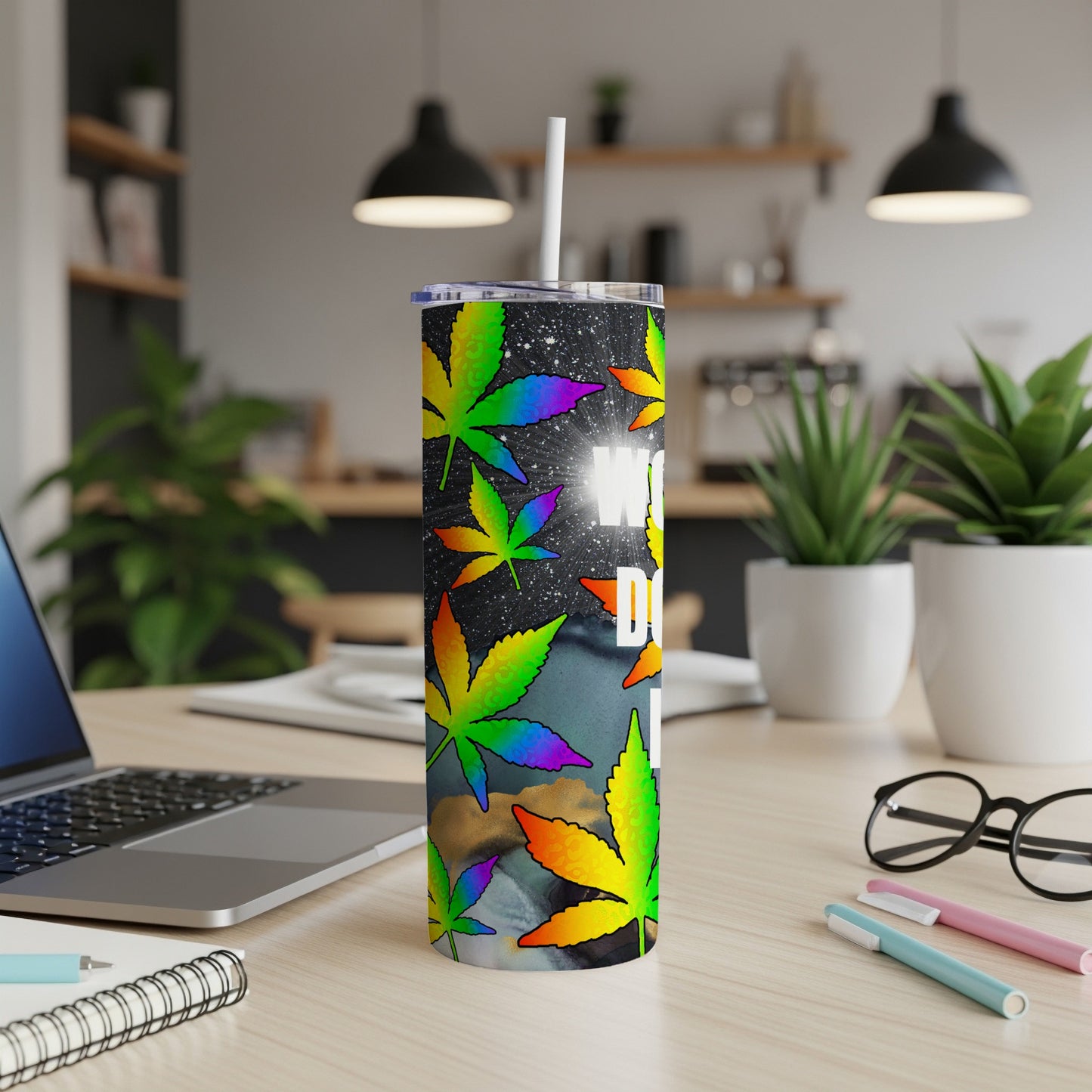 Rainbow cannabis leaves on a starry background wrap around a white tumbler with a straw.