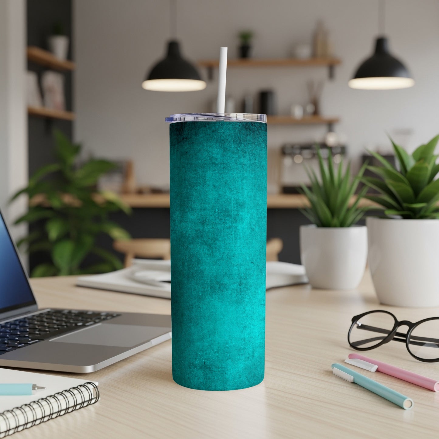 Teal textured tumbler with white straw on a wooden desk.