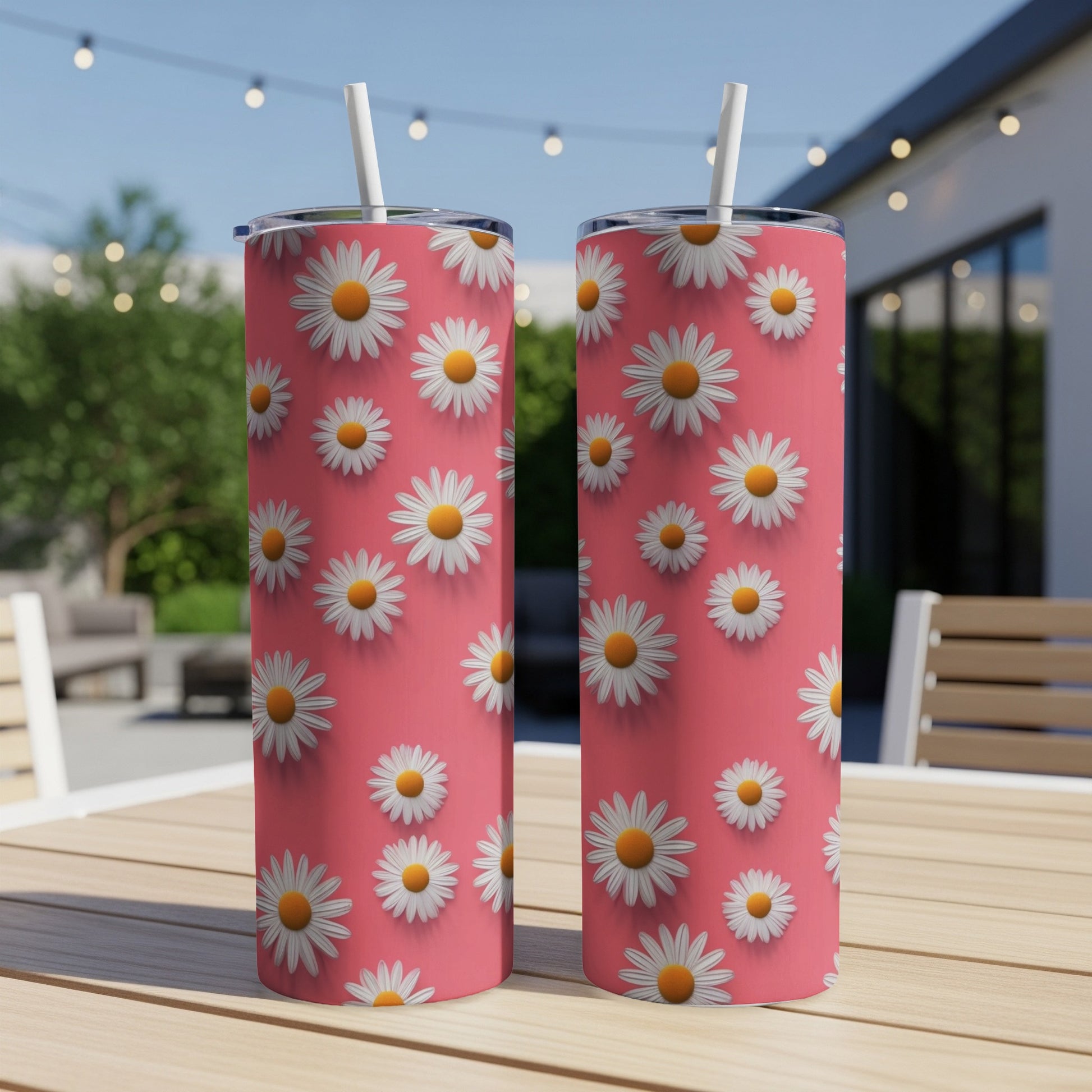 Two tumblers with daisy pattern on pink background on a table.