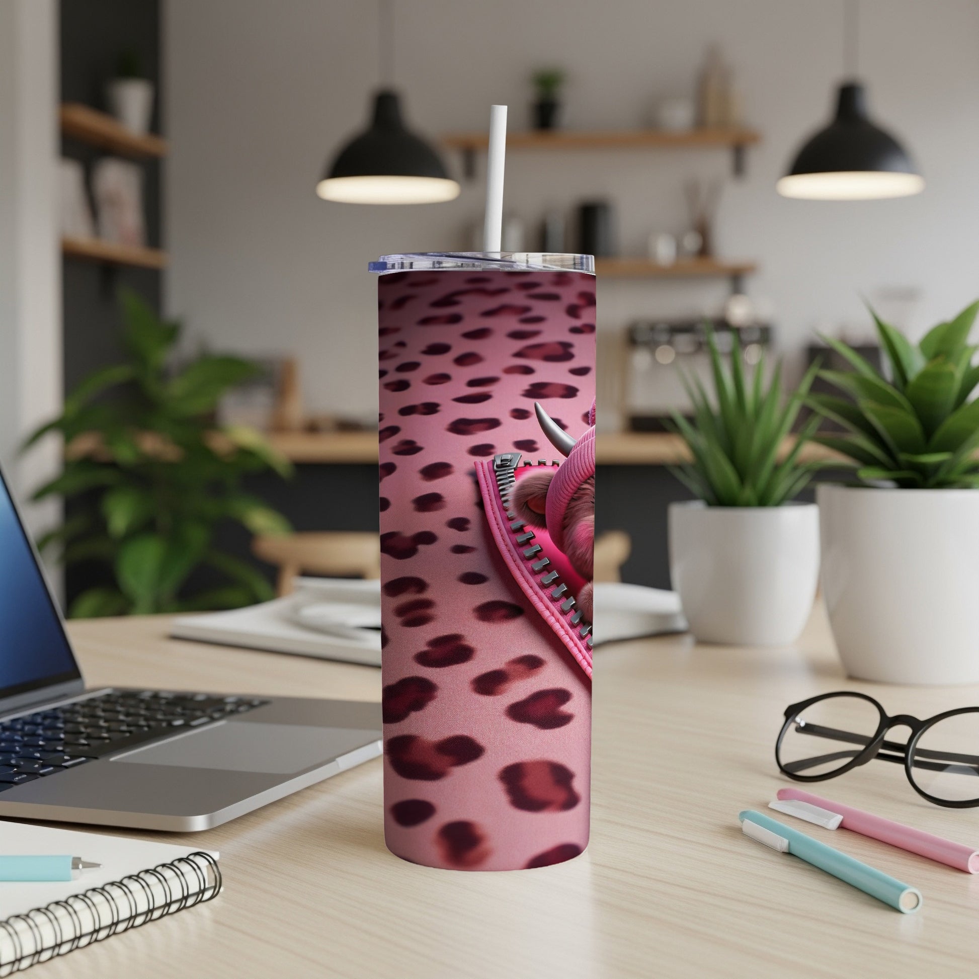 Pink leopard print tumbler with a zipper detail and straw on a desk.