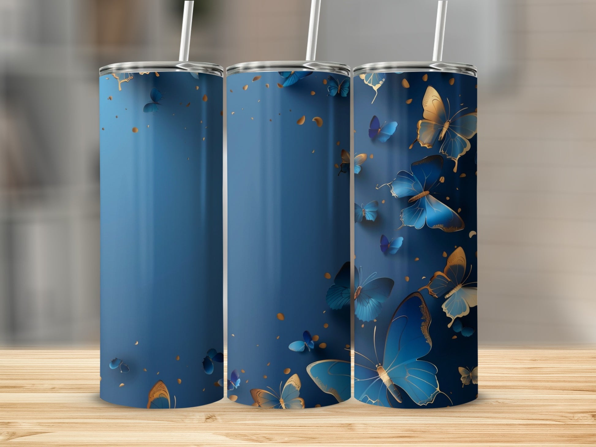 Three blue tumblers with gold and blue butterflies on a wooden surface.