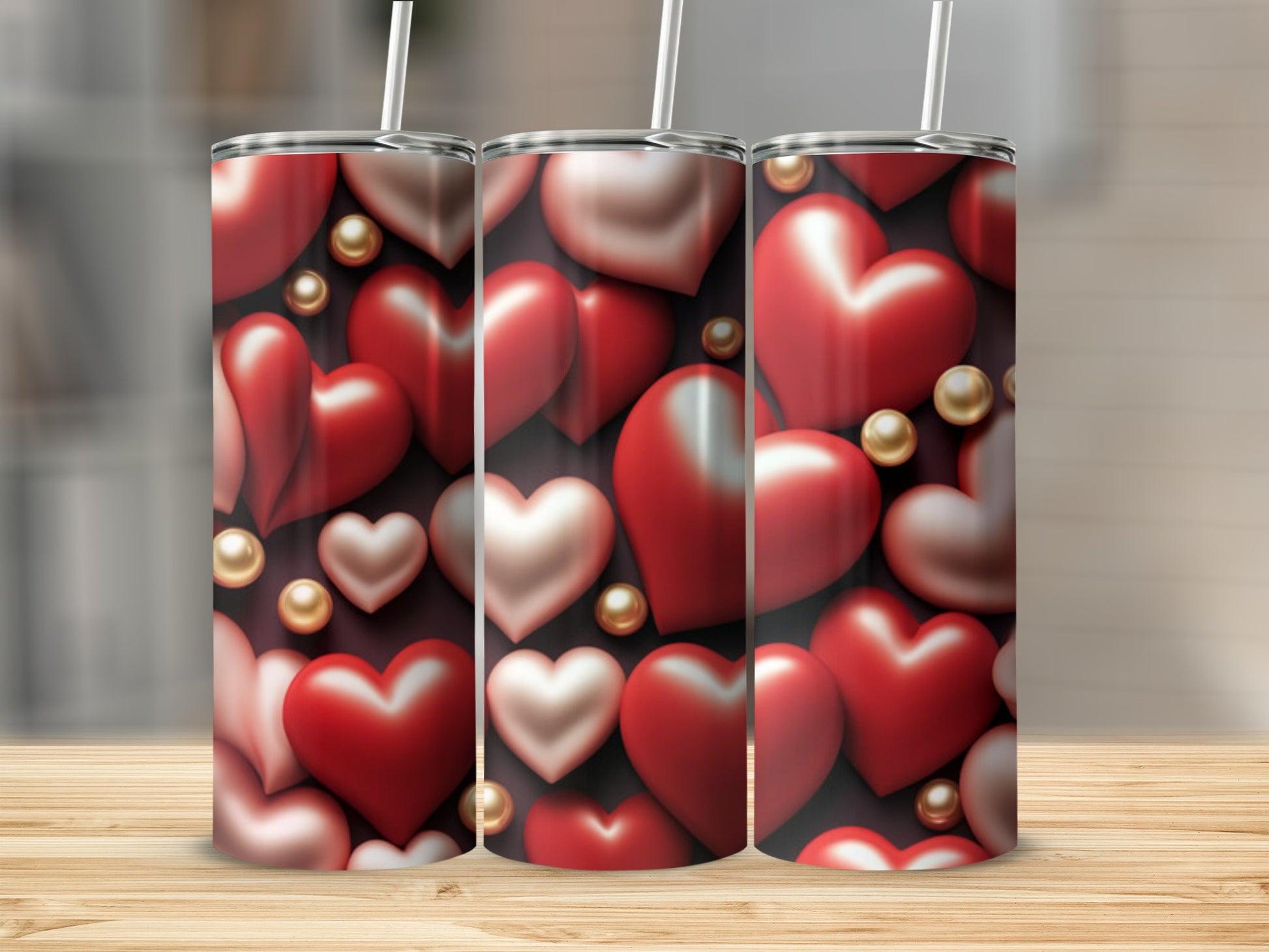 Three tumblers with red and pink hearts and gold pearls on a wooden surface.