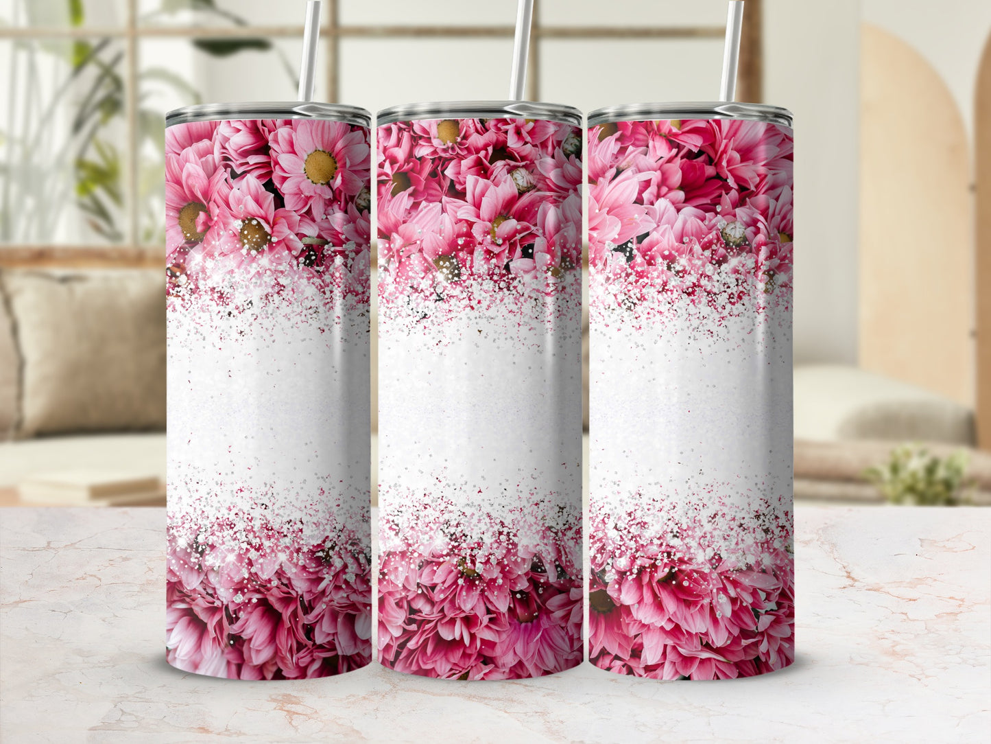 Three pink floral tumblers with glitter accents on a marbled surface.