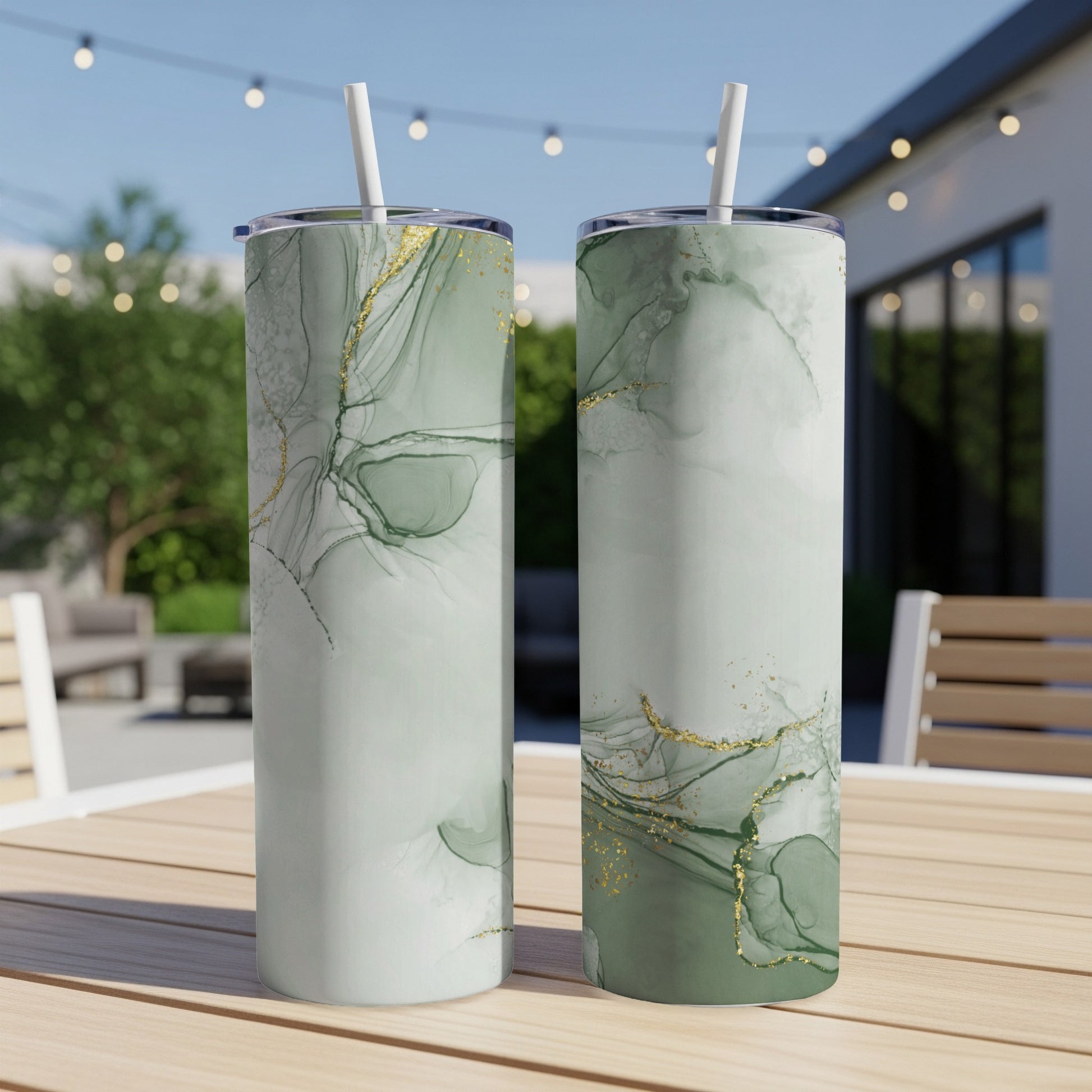 Two green marble tumblers with gold accents on a wooden table.