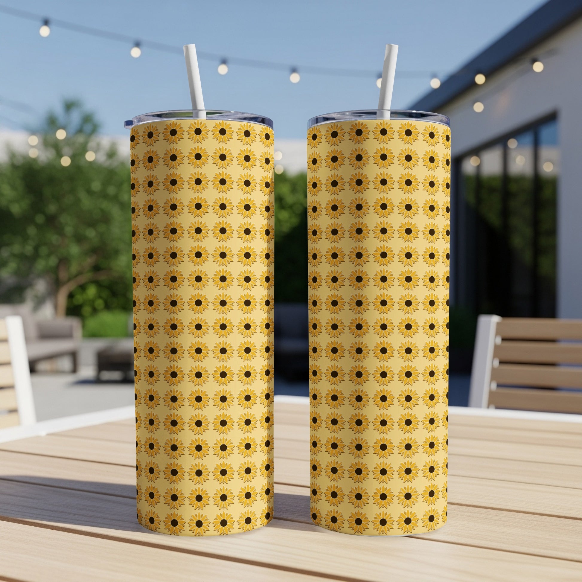 Two tall tumblers with a repeating sunflower pattern on a wooden table.