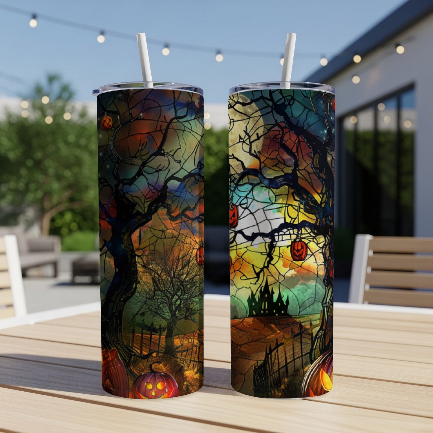 Two Halloween-themed tumblers with pumpkins and spooky trees on a table.