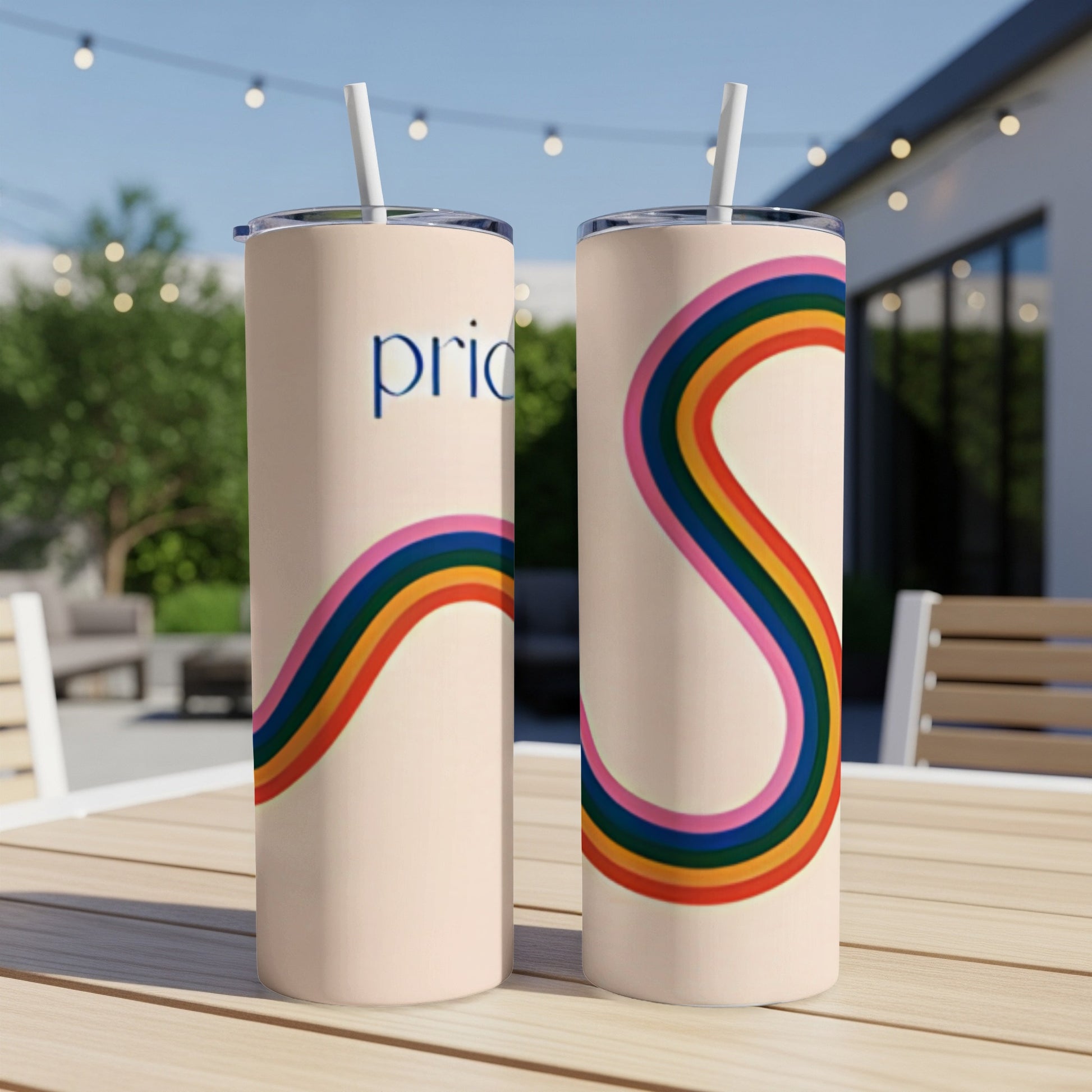Two tumblers with rainbow stripes and "pride" text displayed on a patio table.