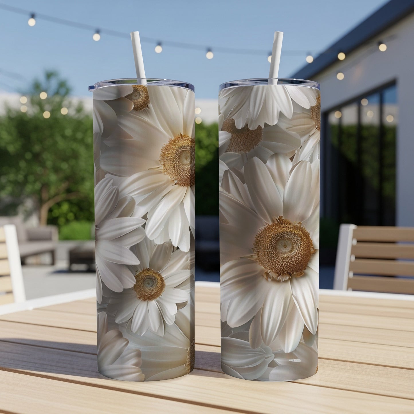 Two tumblers with white daisy pattern on an outdoor table.