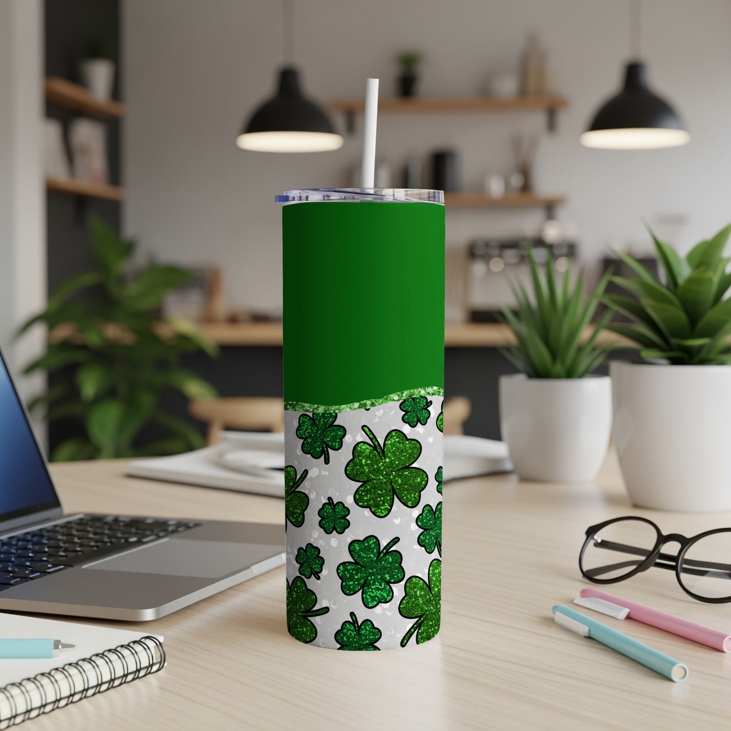 Green tumbler with shamrock pattern, white lid, and straw on desk.