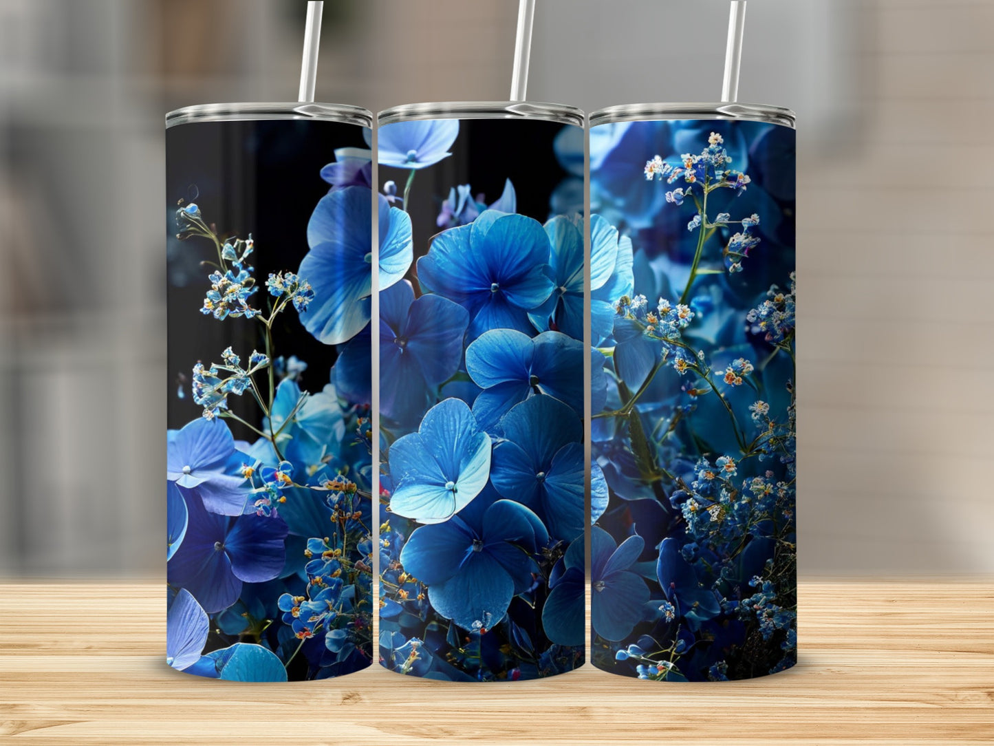 Three tumblers adorned with vibrant blue hydrangea flowers and greenery.