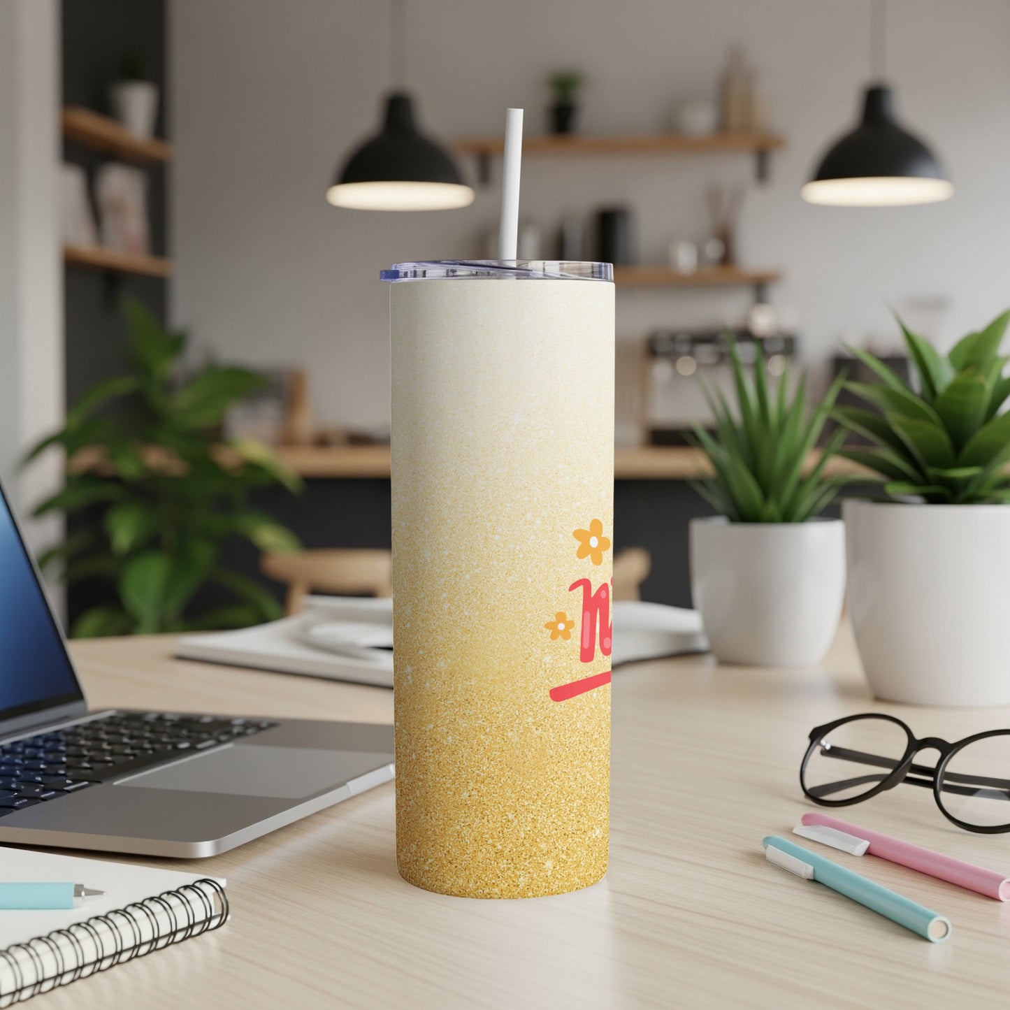 Sparkling gradient tumbler with "Mom" text on a desk with a laptop.