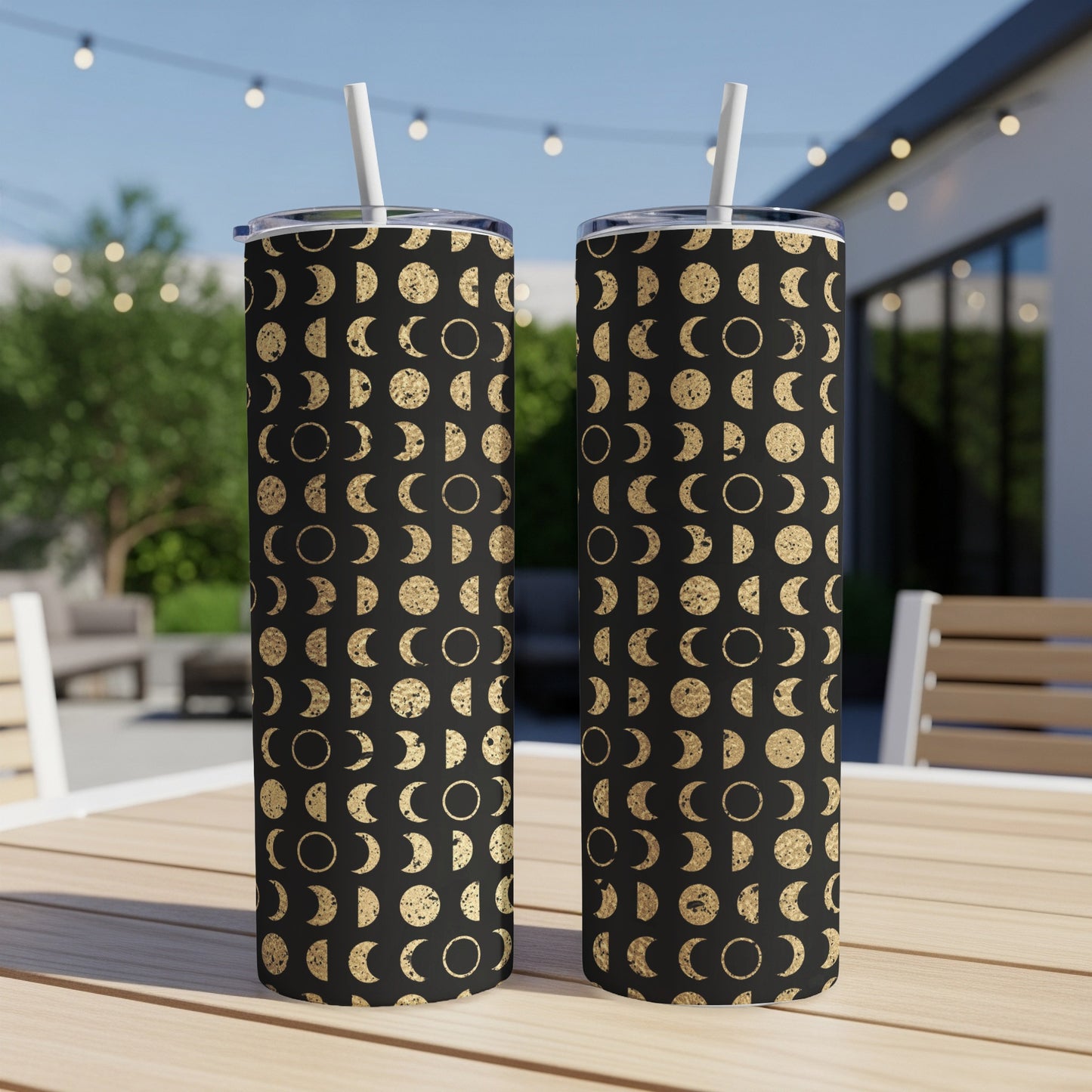 Two tumblers with black background and gold moon phase pattern, each with a white straw.