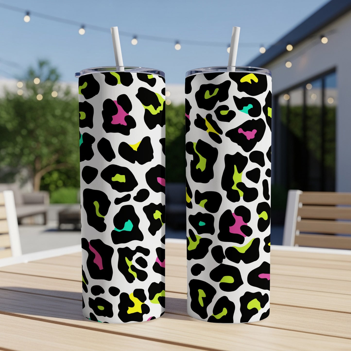 Two tumblers with a colorful leopard print pattern sit on a wooden table.