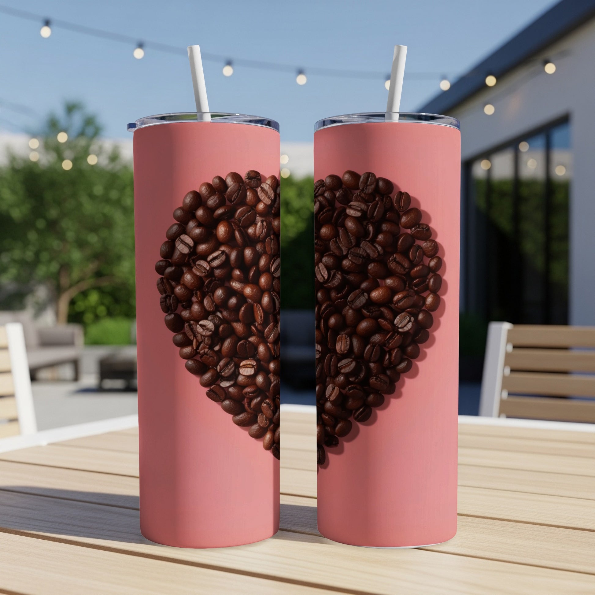 Two pink tumblers on a table, each with half a heart of coffee beans.