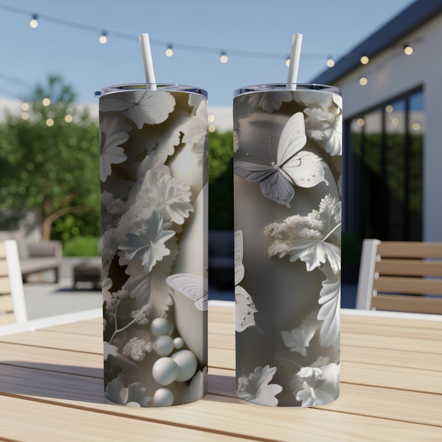 Two tumblers with intricate butterfly and floral designs displayed on a table.