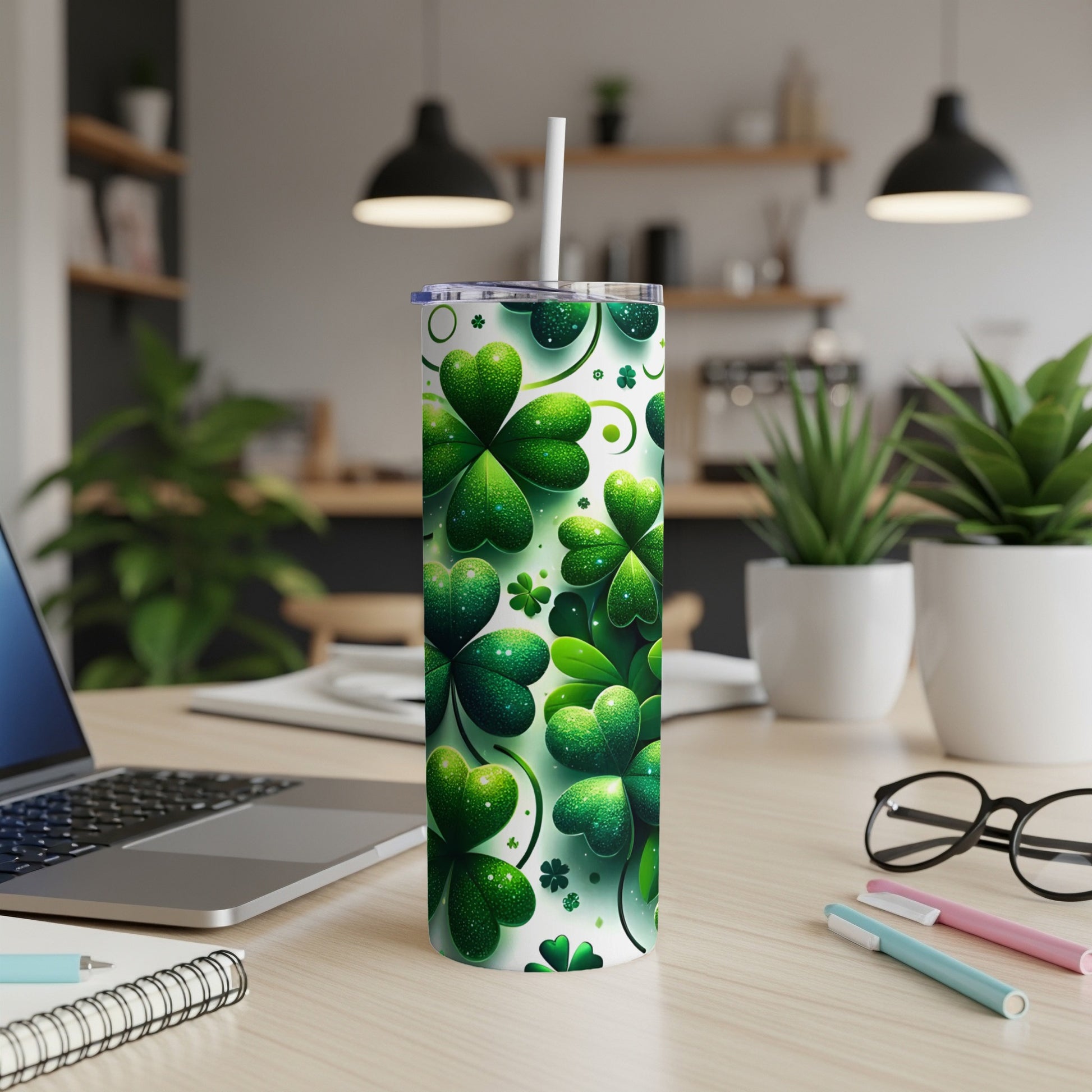 Green shamrock-patterned tumbler with a white straw on a desk.