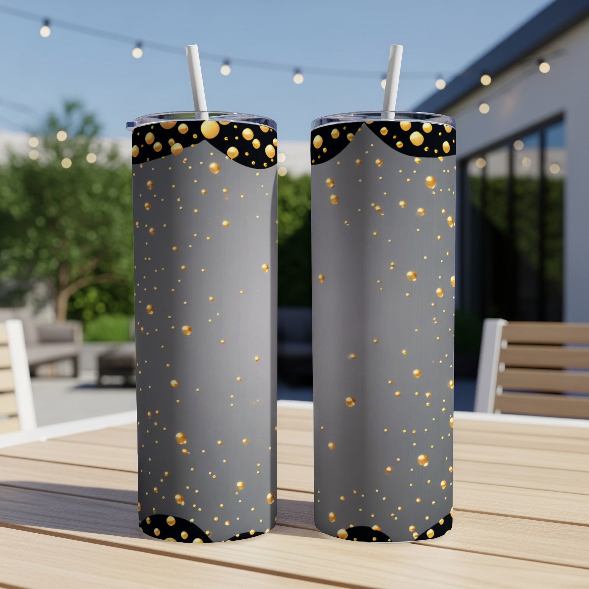Two gray tumblers with gold dots and black scalloped trim sit on a table.