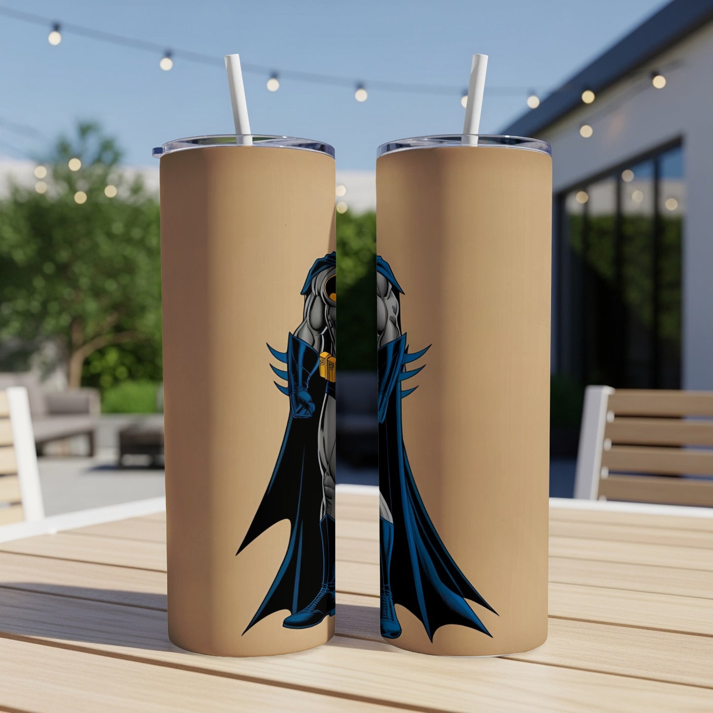 Two tan tumblers with Batman graphic, standing on a wooden table outdoors.