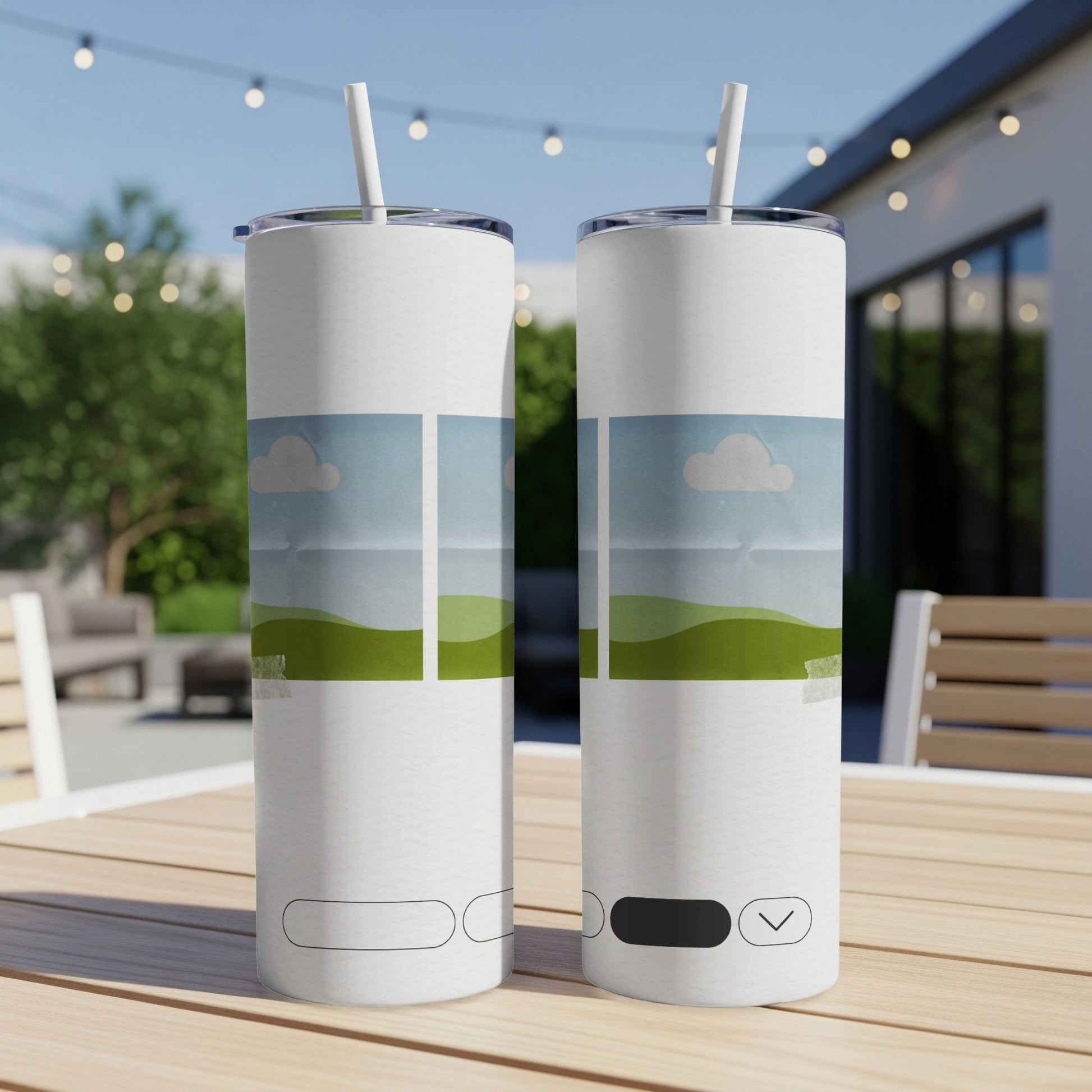 Two white tumblers with a landscape design sit on a wooden table outdoors.