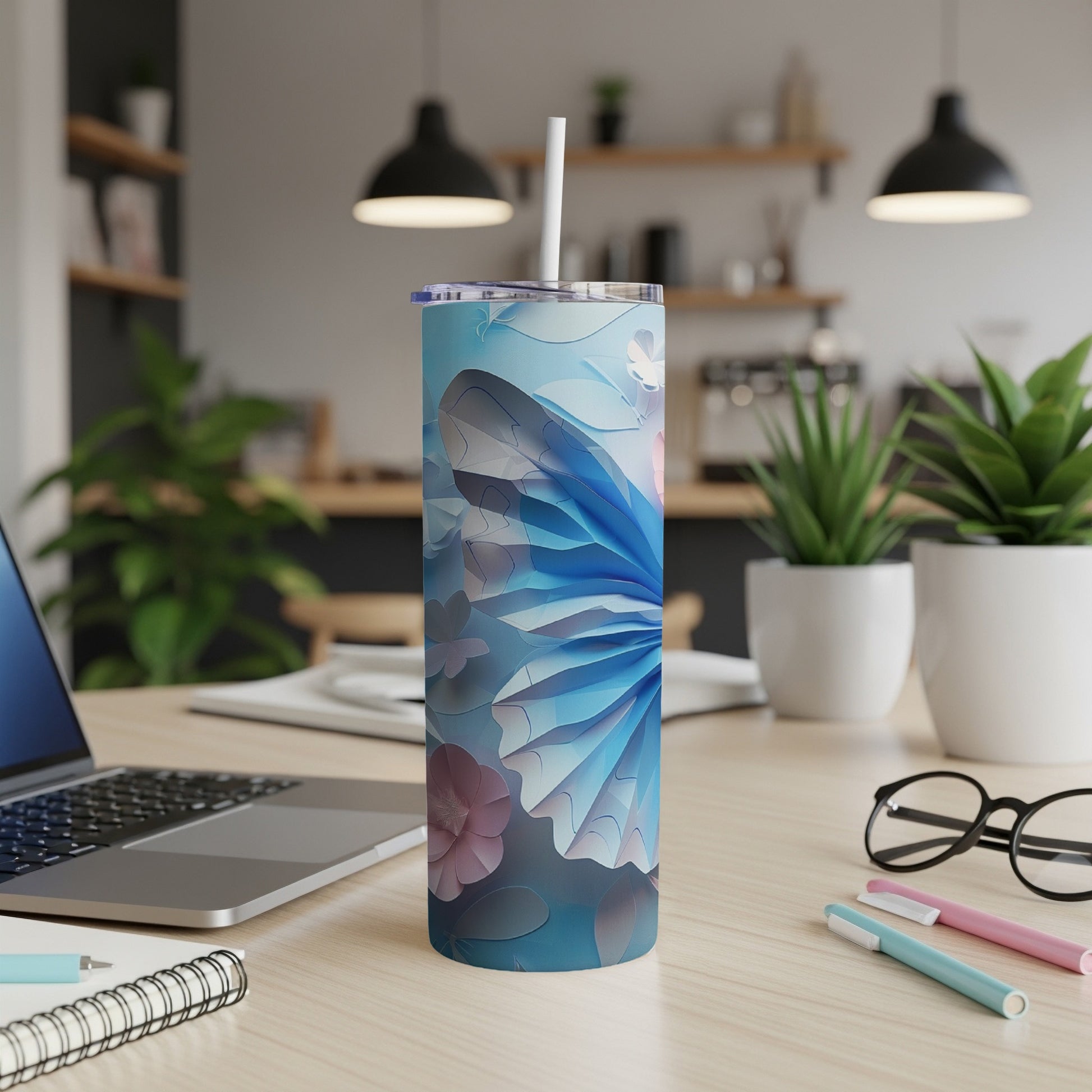 Blue butterfly patterned tumbler with straw on a desk.