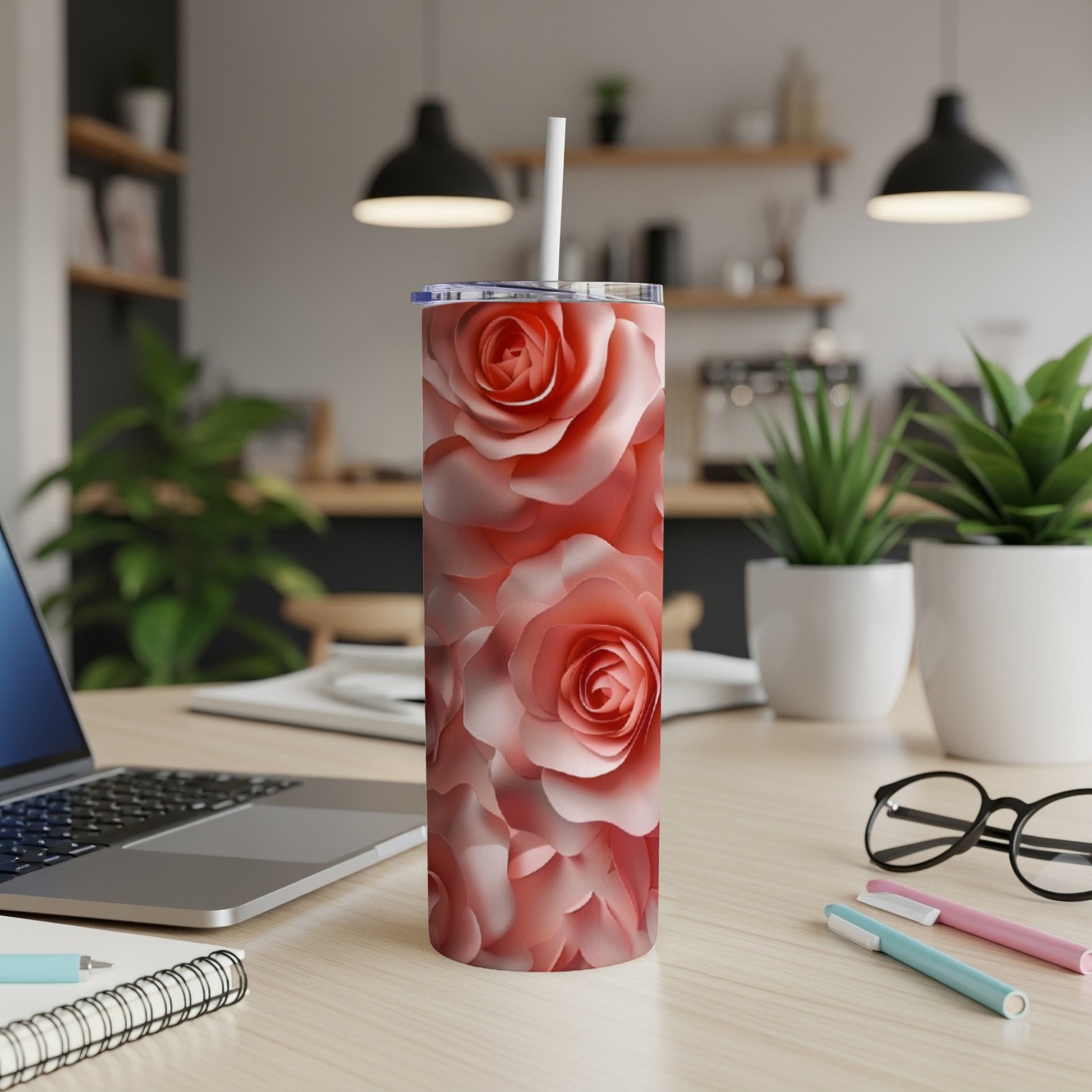 Pink roses pattern on a stainless steel tumbler with a straw on a desk.
