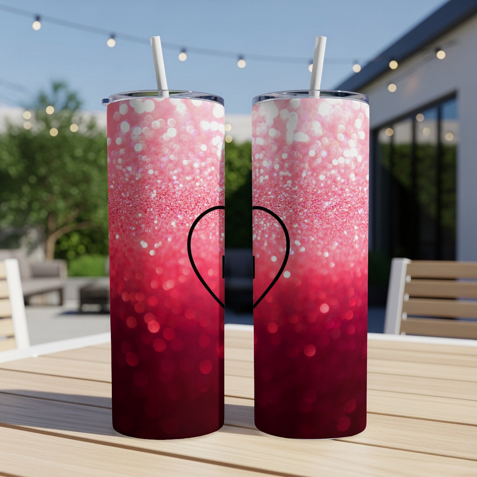 Two tumblers with a pink and red glitter ombre design and a black heart.