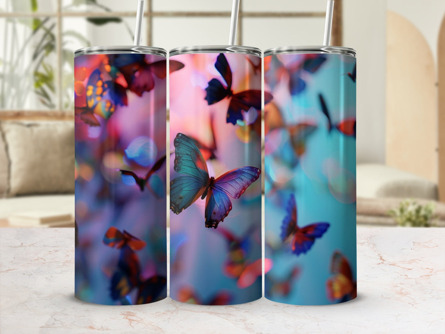 Three tumblers with colorful butterfly designs, set against a blurred background.