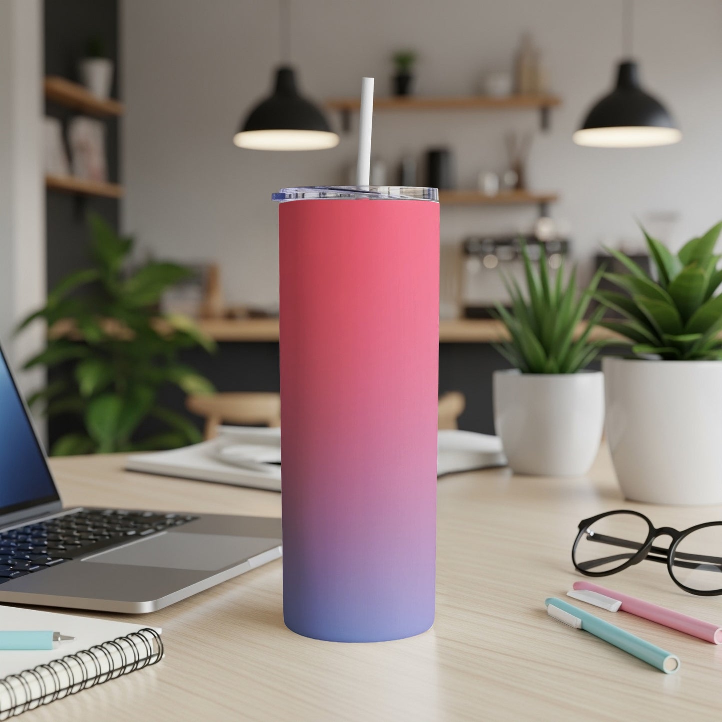 Gradient pink to blue insulated tumbler with straw on a desk.