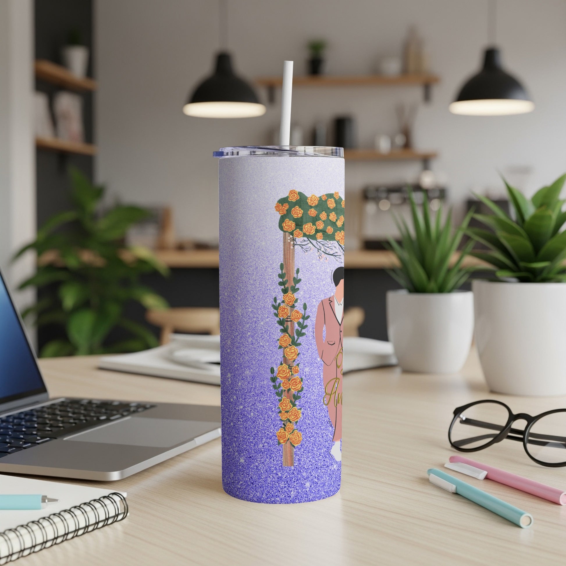 Purple tumbler with floral design and straw on a desk.