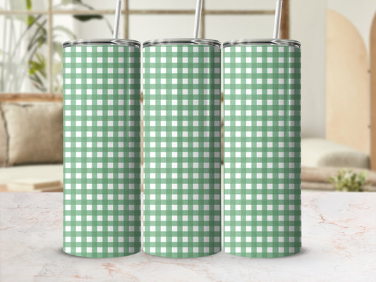 Three green and white checkered tumblers with straws stand on a counter.