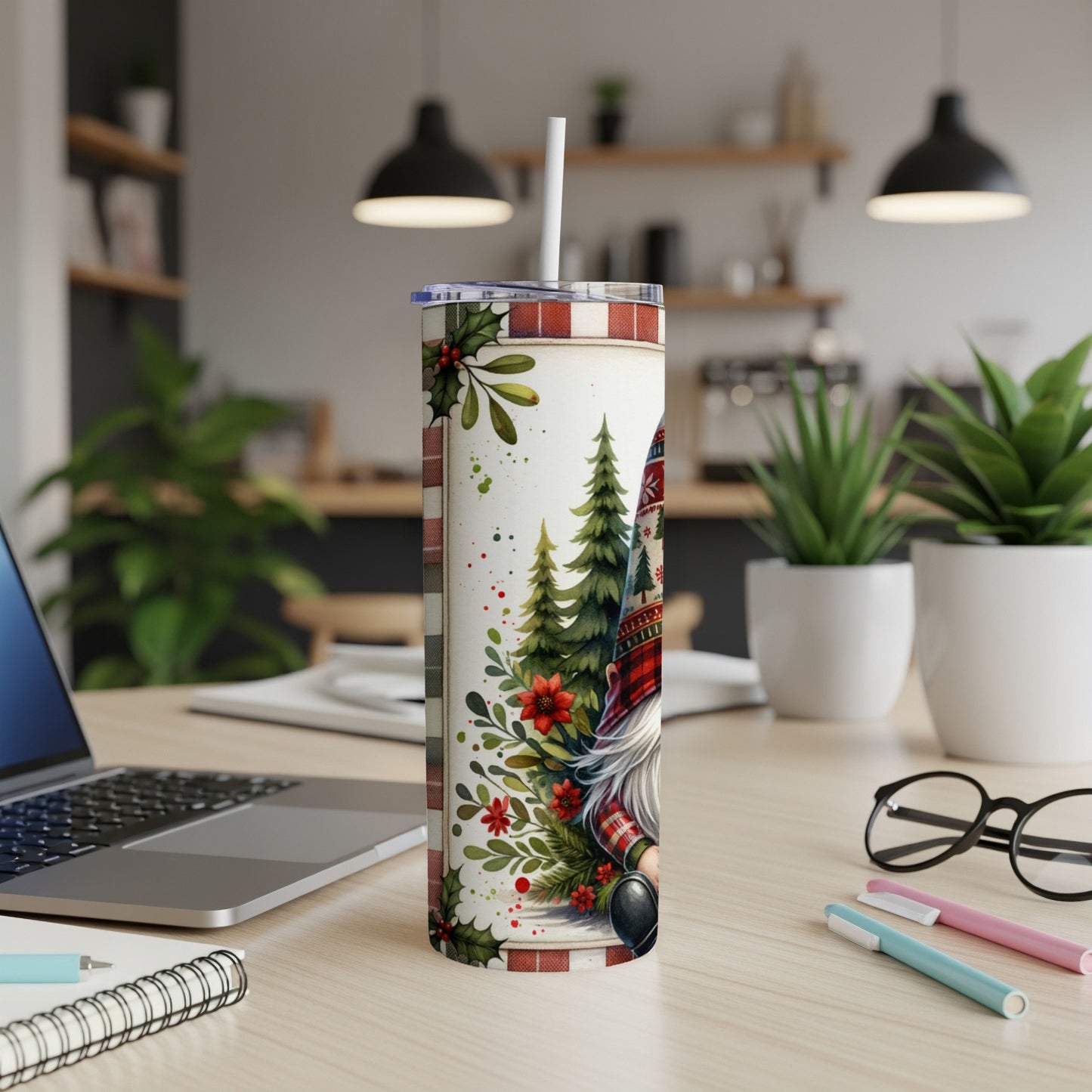 Christmas gnome tumbler with plaid hat and snowflakes on a desk.