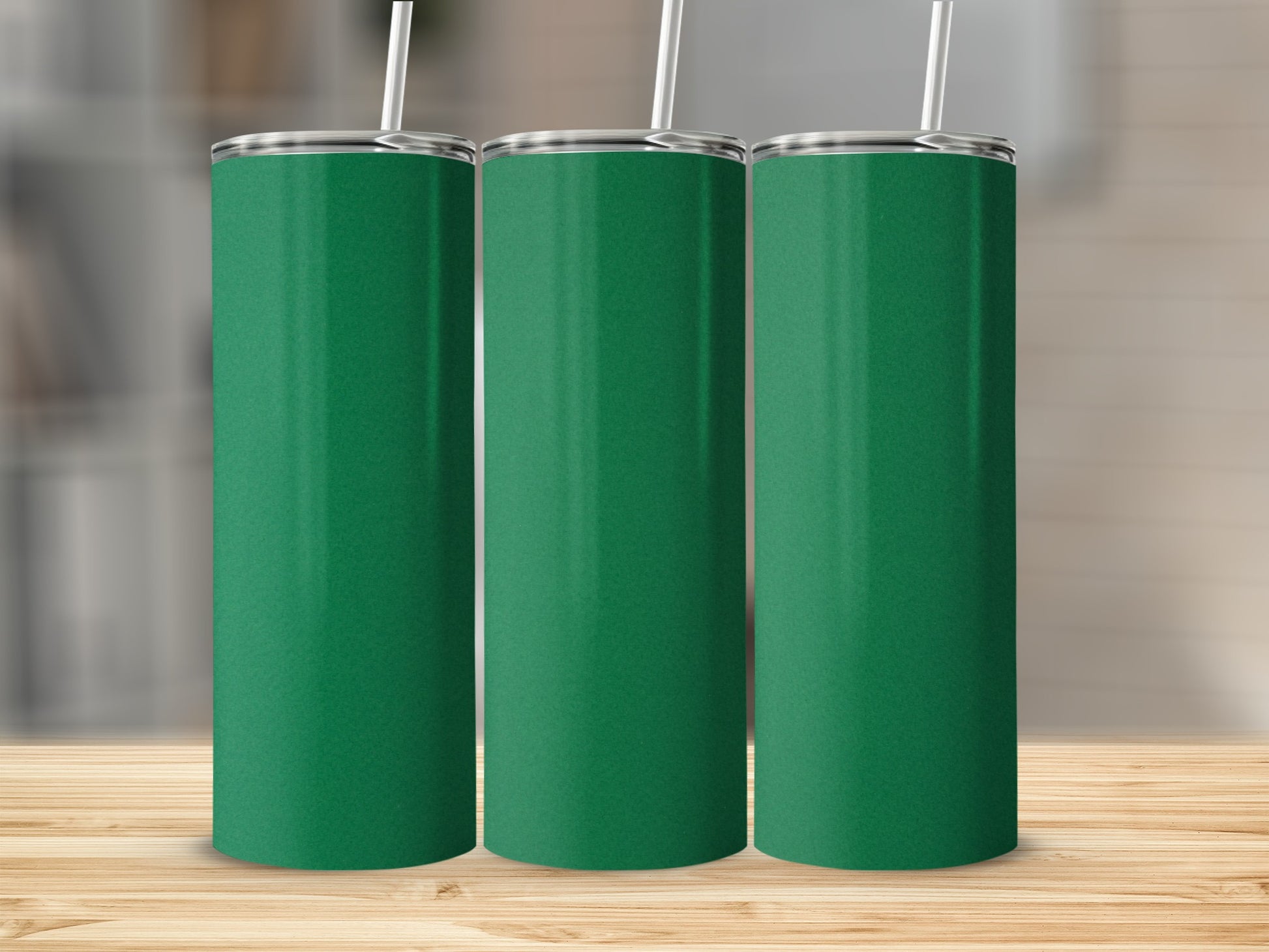 Three tall, green tumblers with white straws stand on a wooden surface.