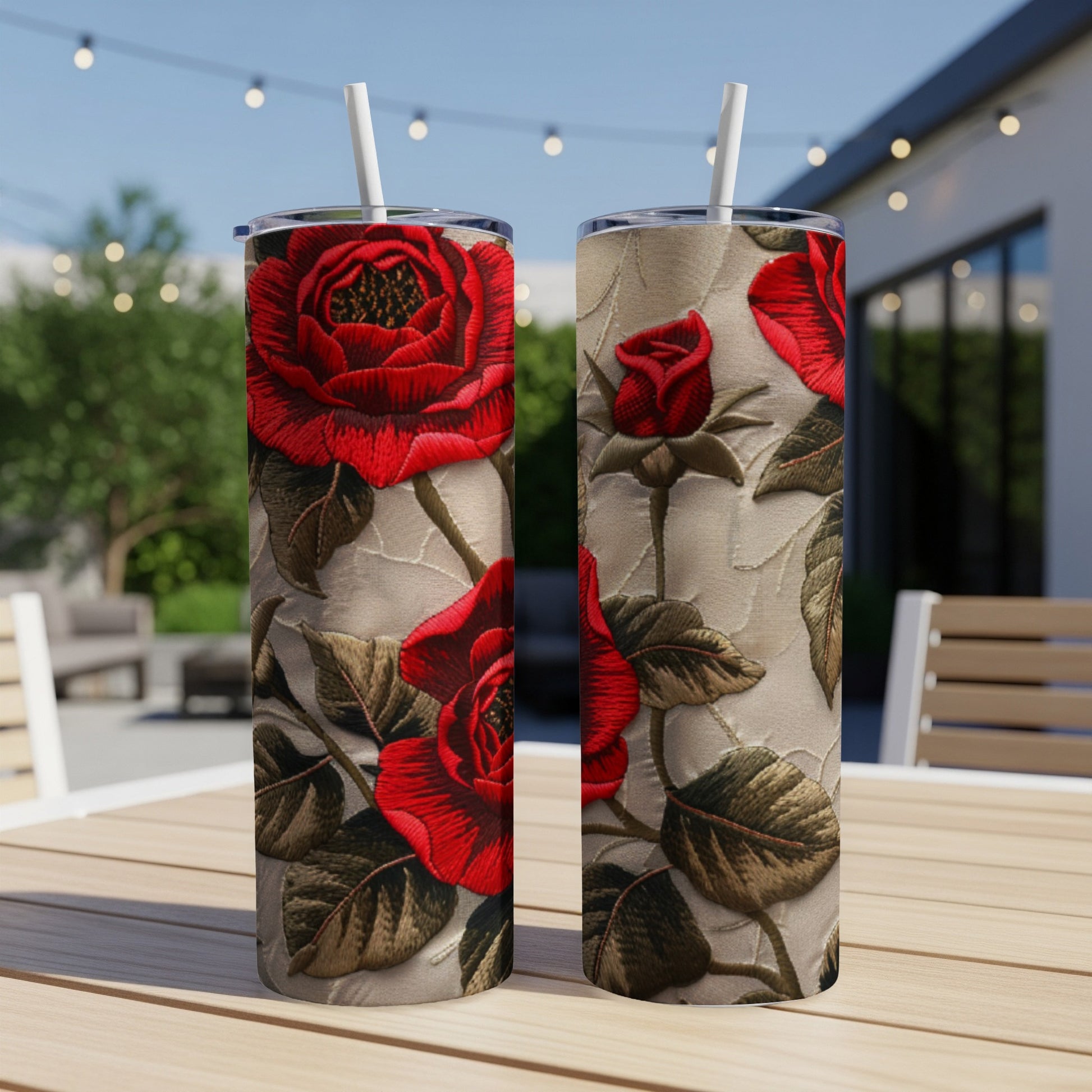 Two tumblers with red rose embroidery pattern on a table.