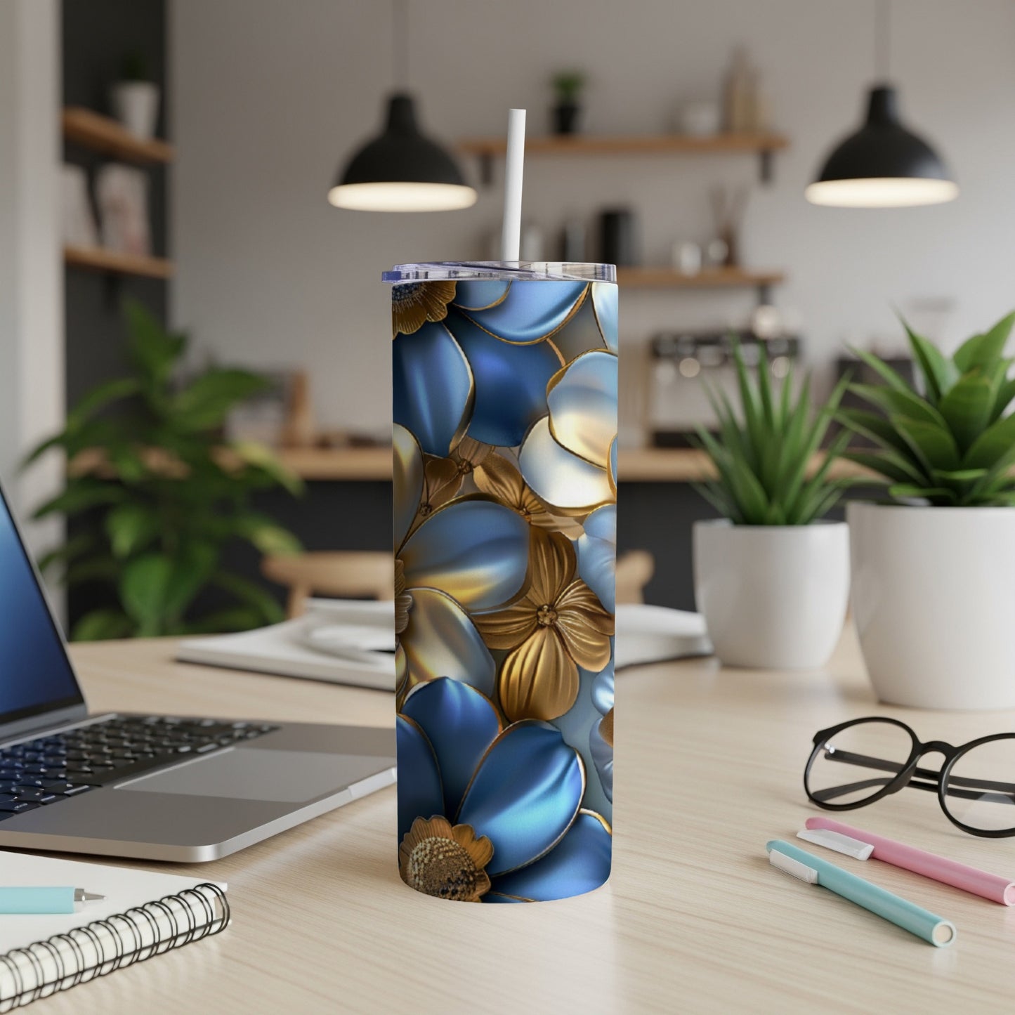 Blue and gold floral patterned tumbler with straw on a desk.