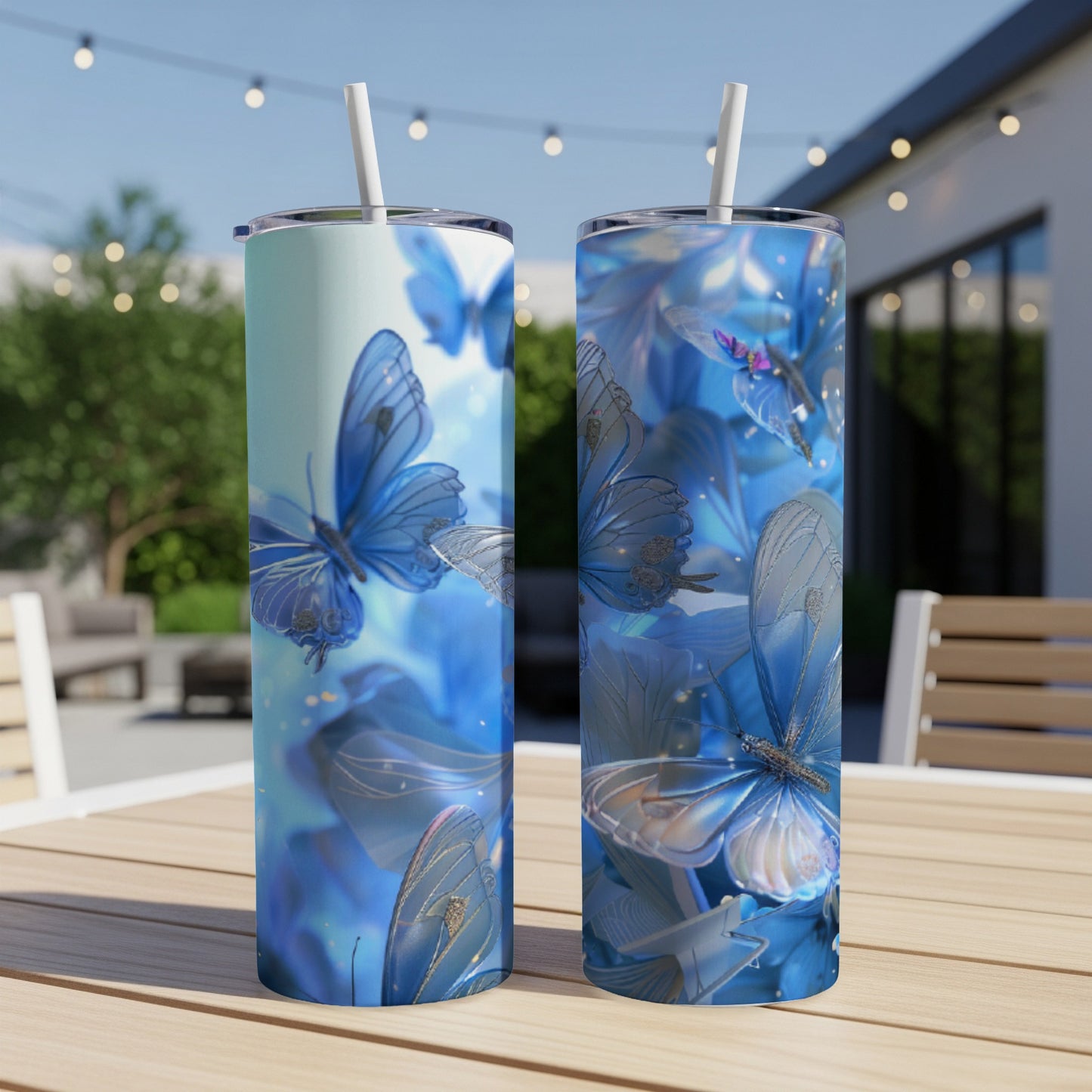 Two blue butterfly tumblers with straws on a wooden table.