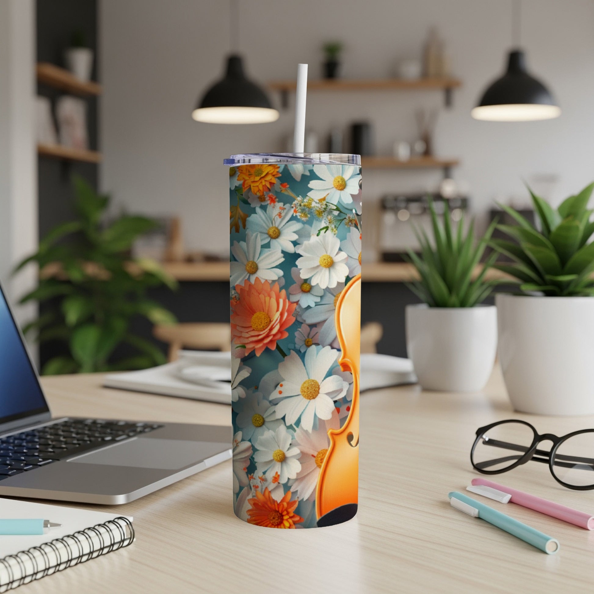 Tall tumbler with a floral and violin design, set on a desk.