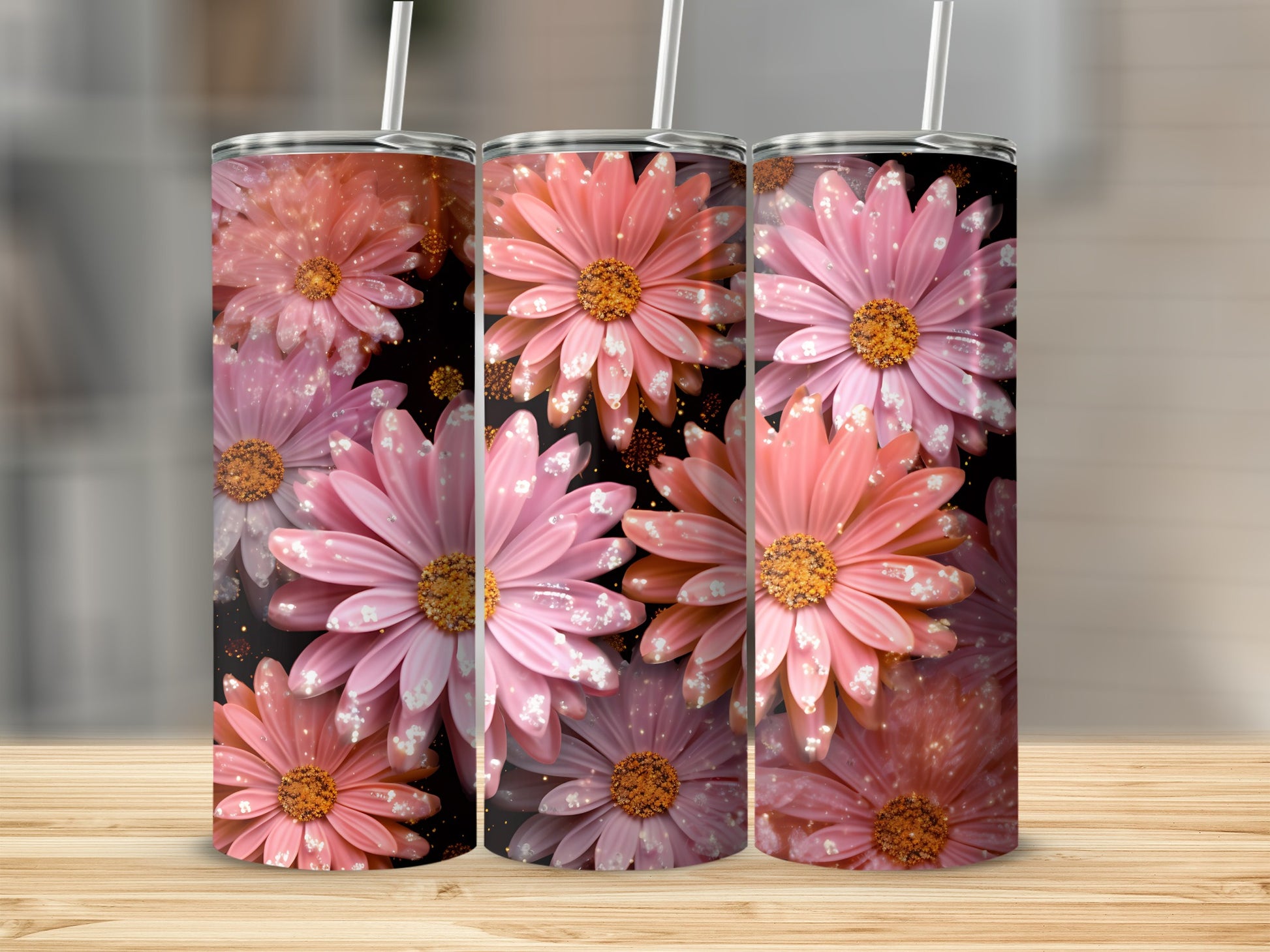 Three pink floral tumblers with glitter accents on a wooden surface.