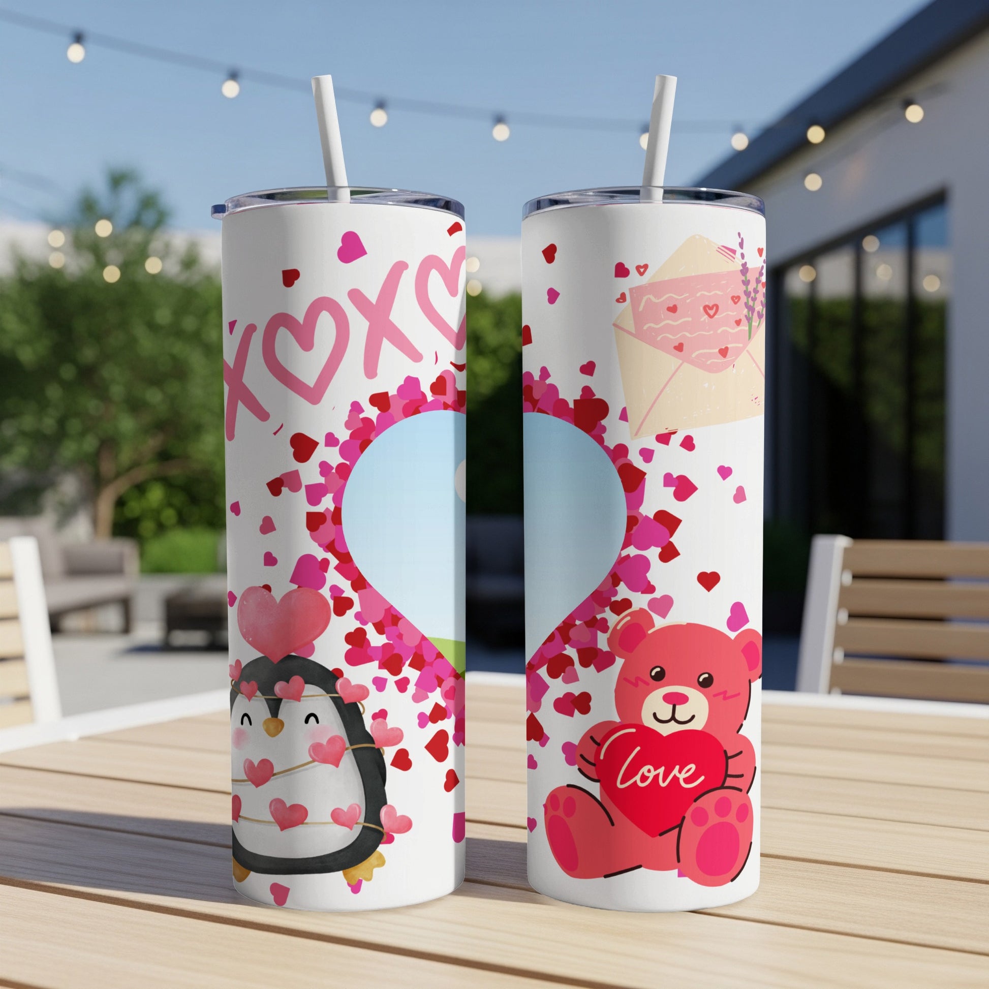Two Valentine's themed tumblers, one with a penguin, one with a bear, on a table.