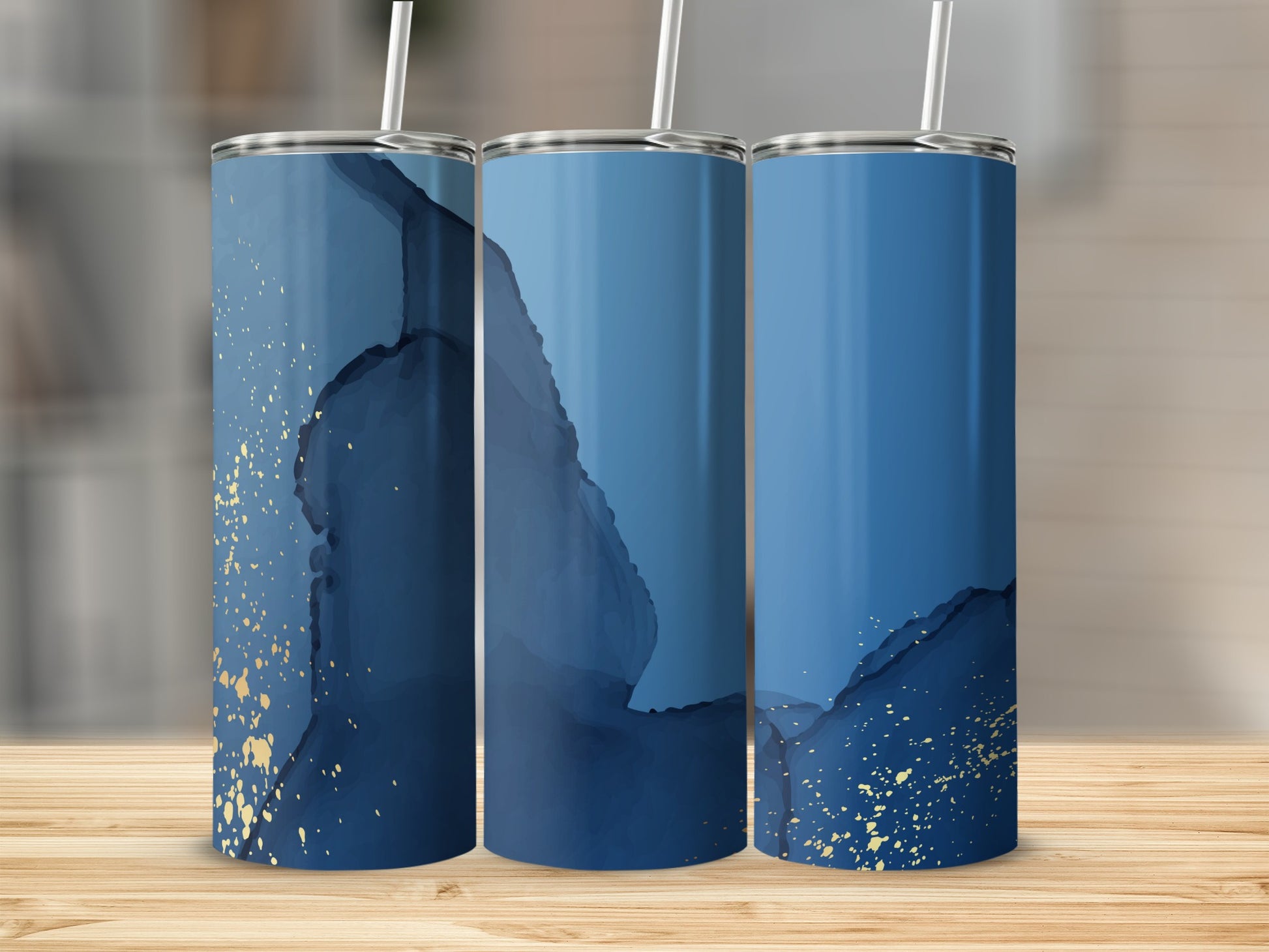 Three blue and gold abstract pattern tumblers on a wooden surface.
