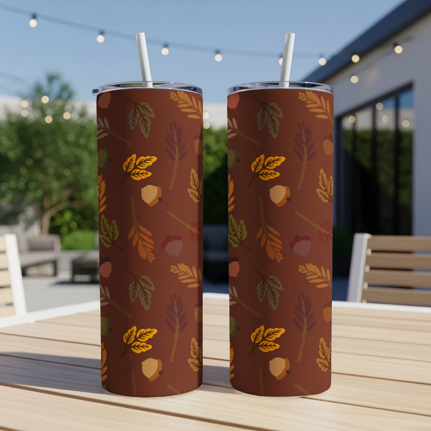 Two tumblers with autumn leaf and acorn pattern on a patio table.